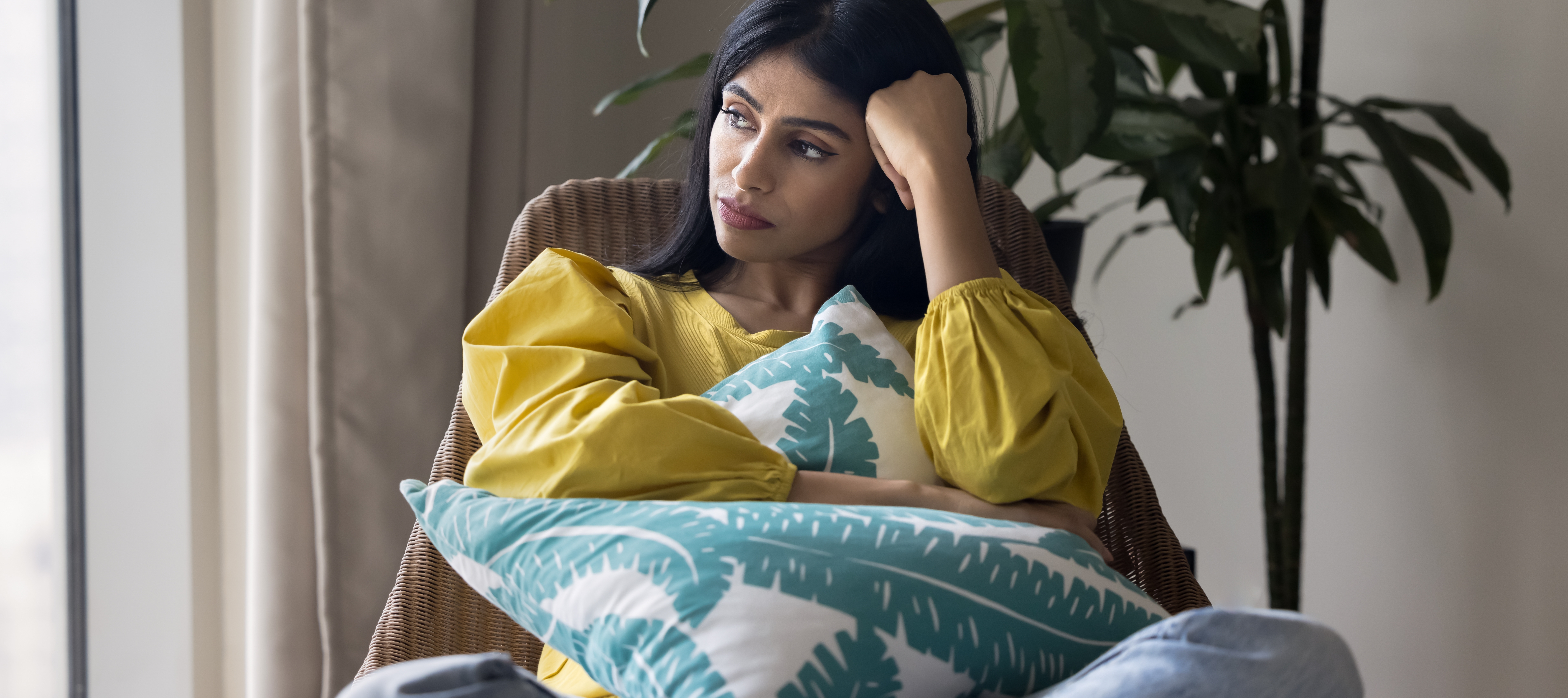 A woman sits pensively in her living room.