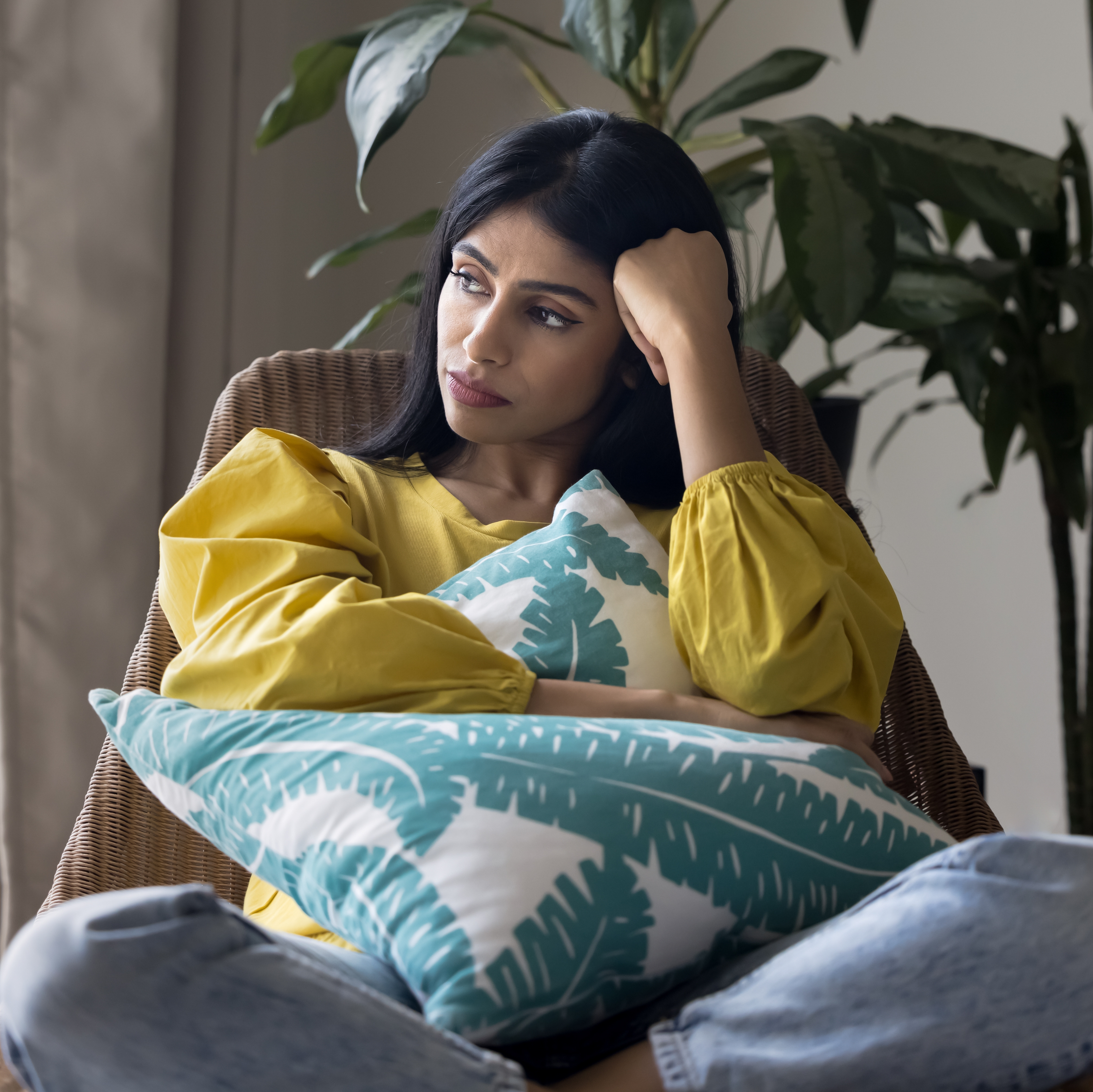 A woman sits pensively in her living room.