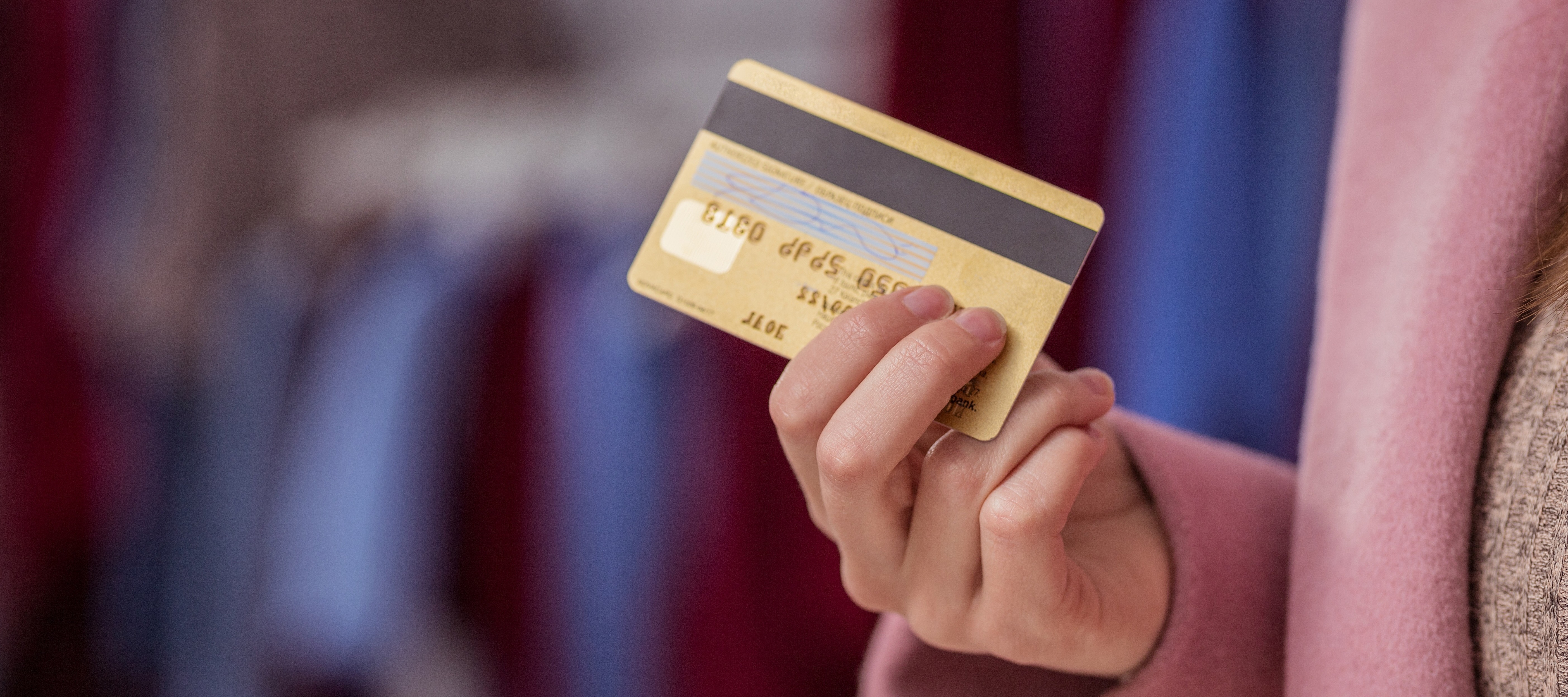 A well-dressed woman carries a gold-colored credit card.