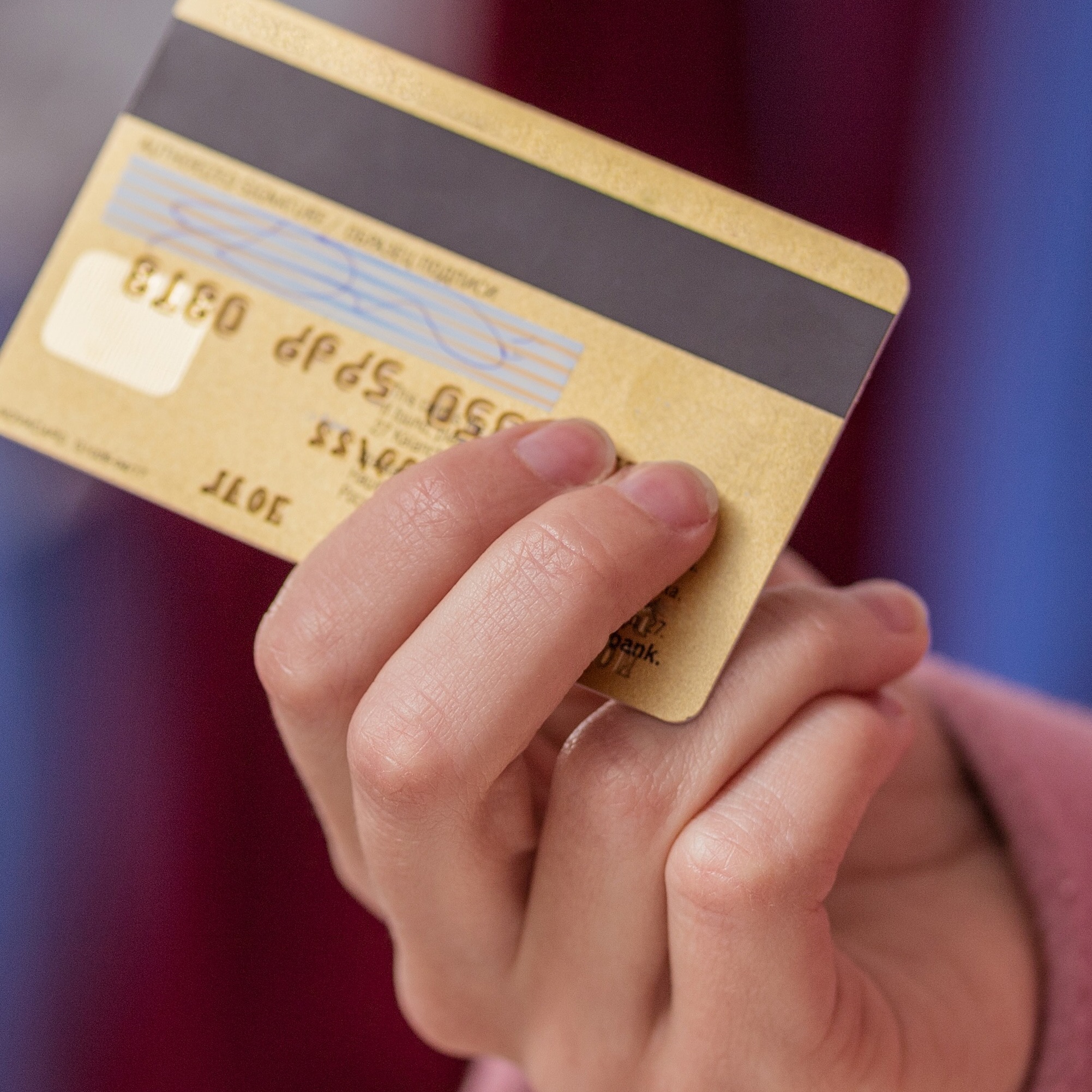 A well-dressed woman carries a gold-colored credit card.