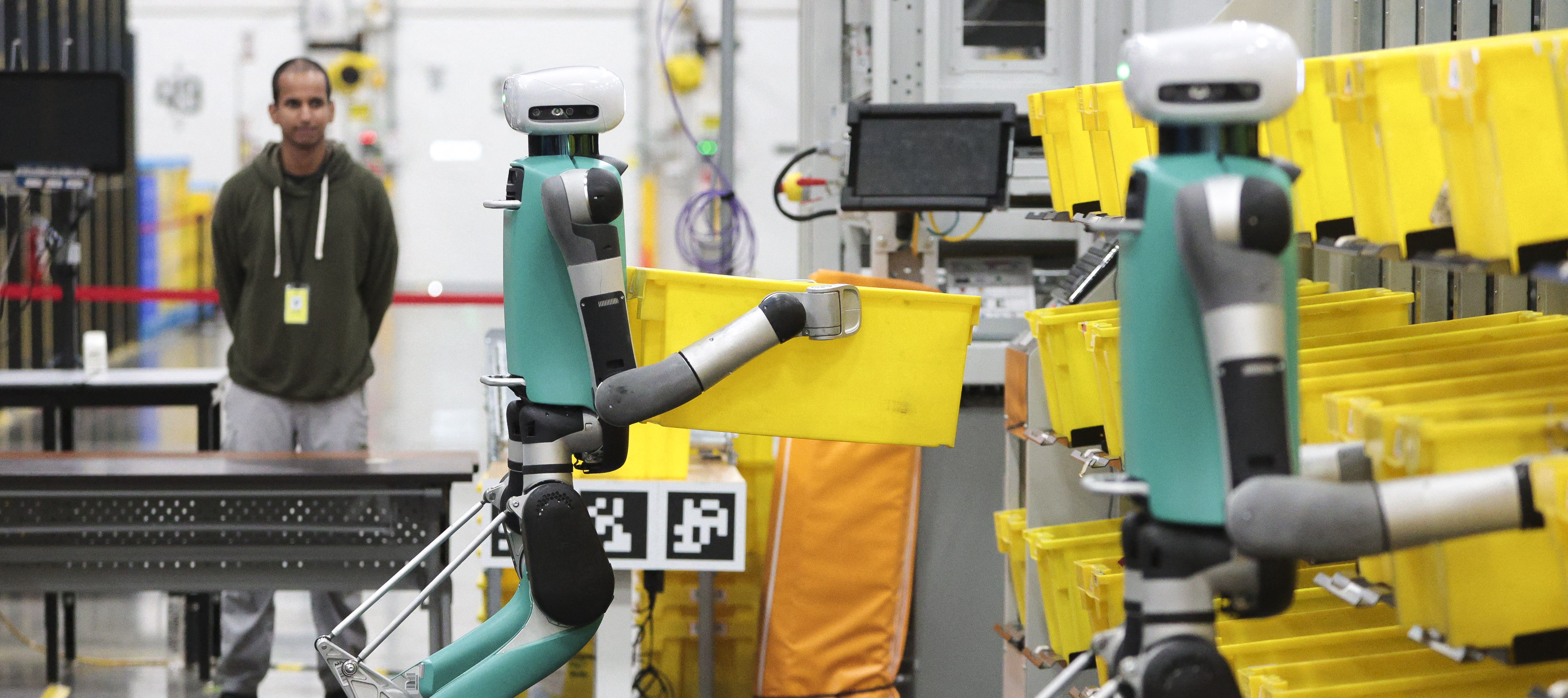 Bipedal robots move containers during a demonstration at an Amazon fulfillment center in Sumner, Washington, Oct. 18, 2023.