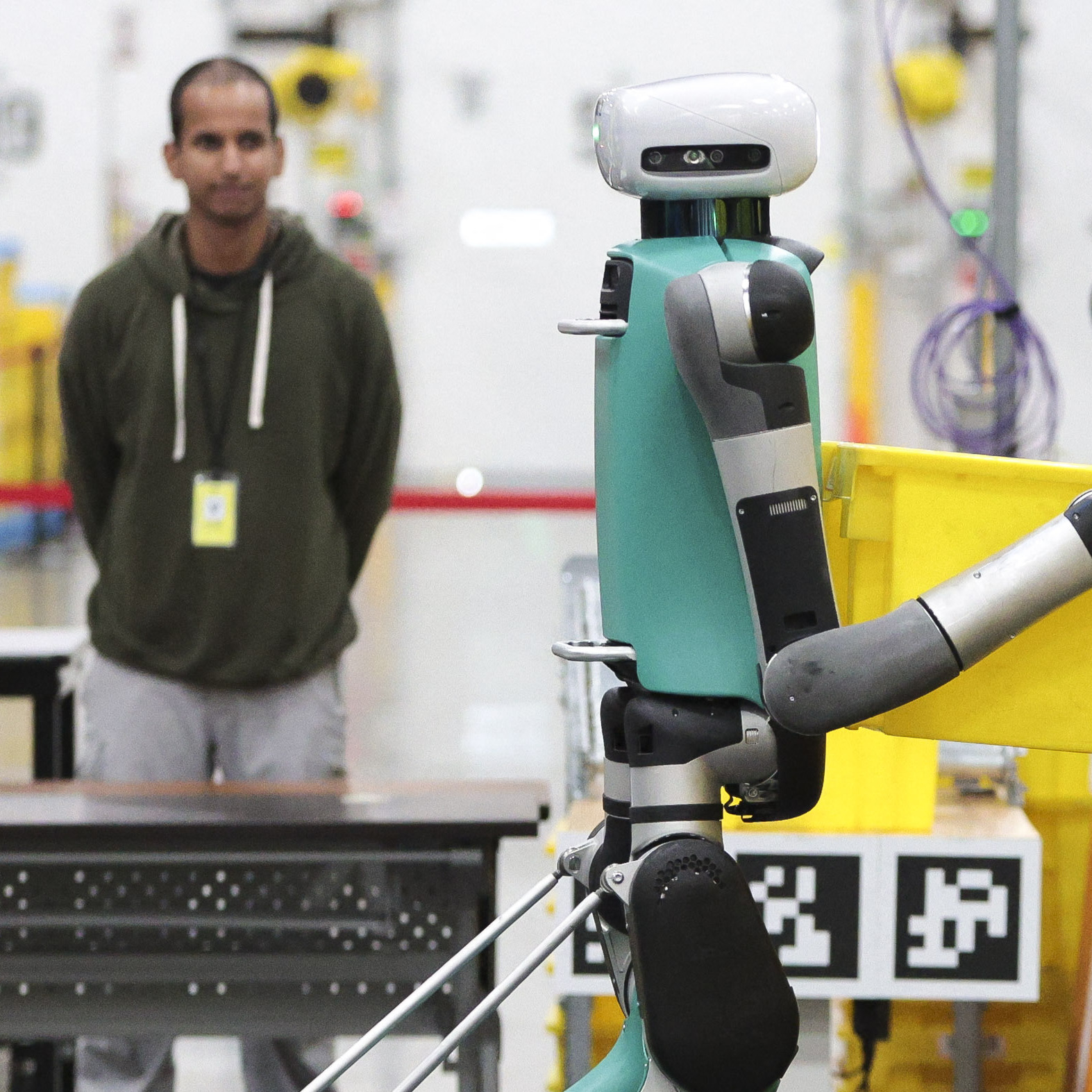 Bipedal robots move containers during a demonstration at an Amazon fulfillment center in Sumner, Washington, Oct. 18, 2023.
