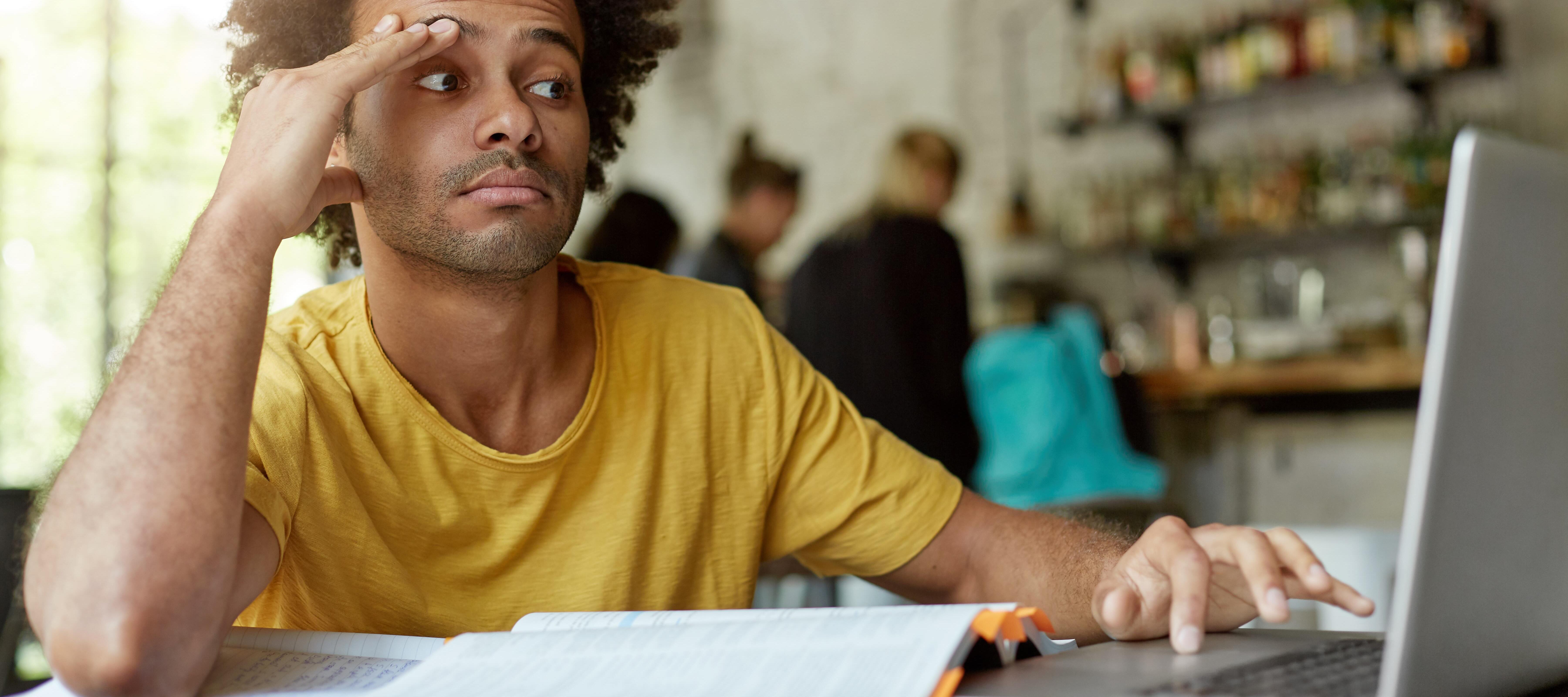 A man looks confused in front of his laptop, as he prepares to file years of tax returns.