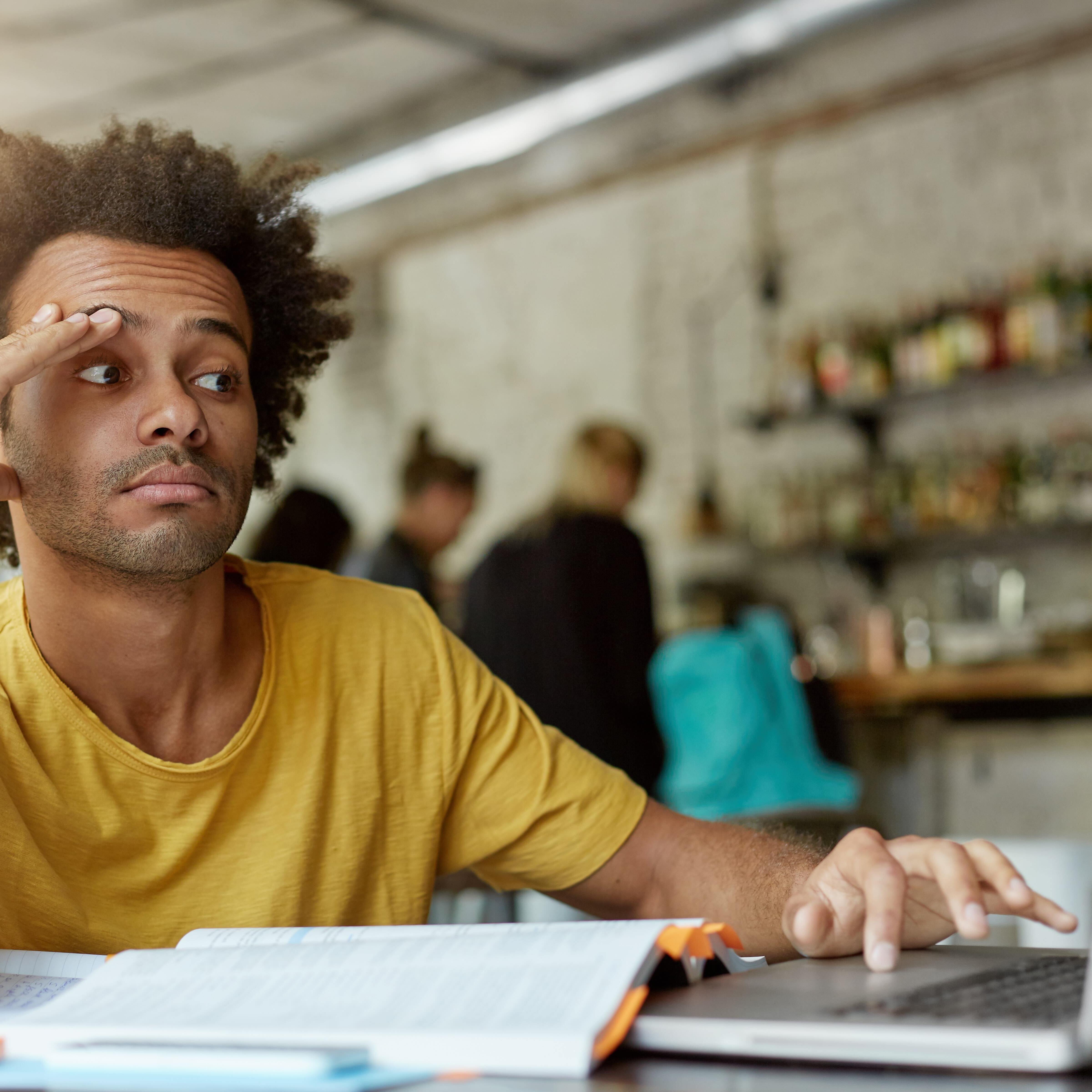A man looks confused in front of his laptop, as he prepares to file years of tax returns.