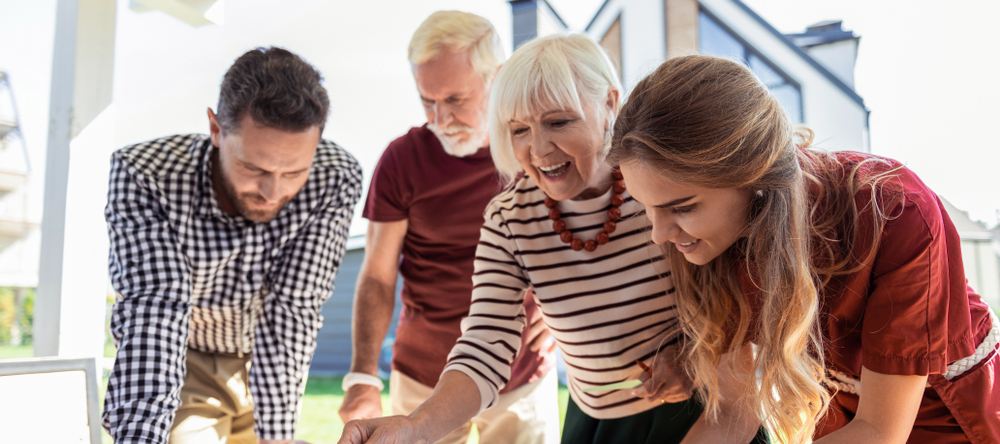 Millennial couple with boomer parents playing a game outside.