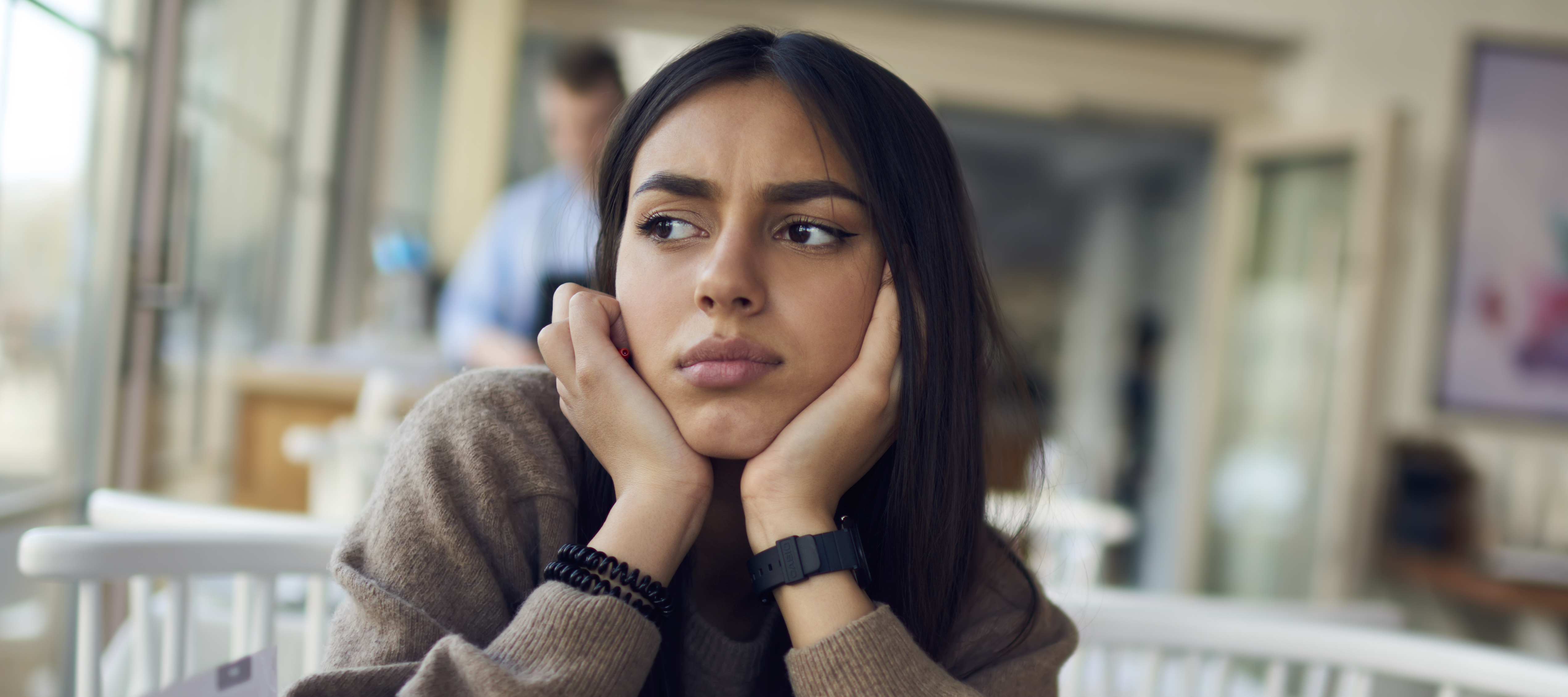 A young woman looking stressed out rests her chin against both palms.