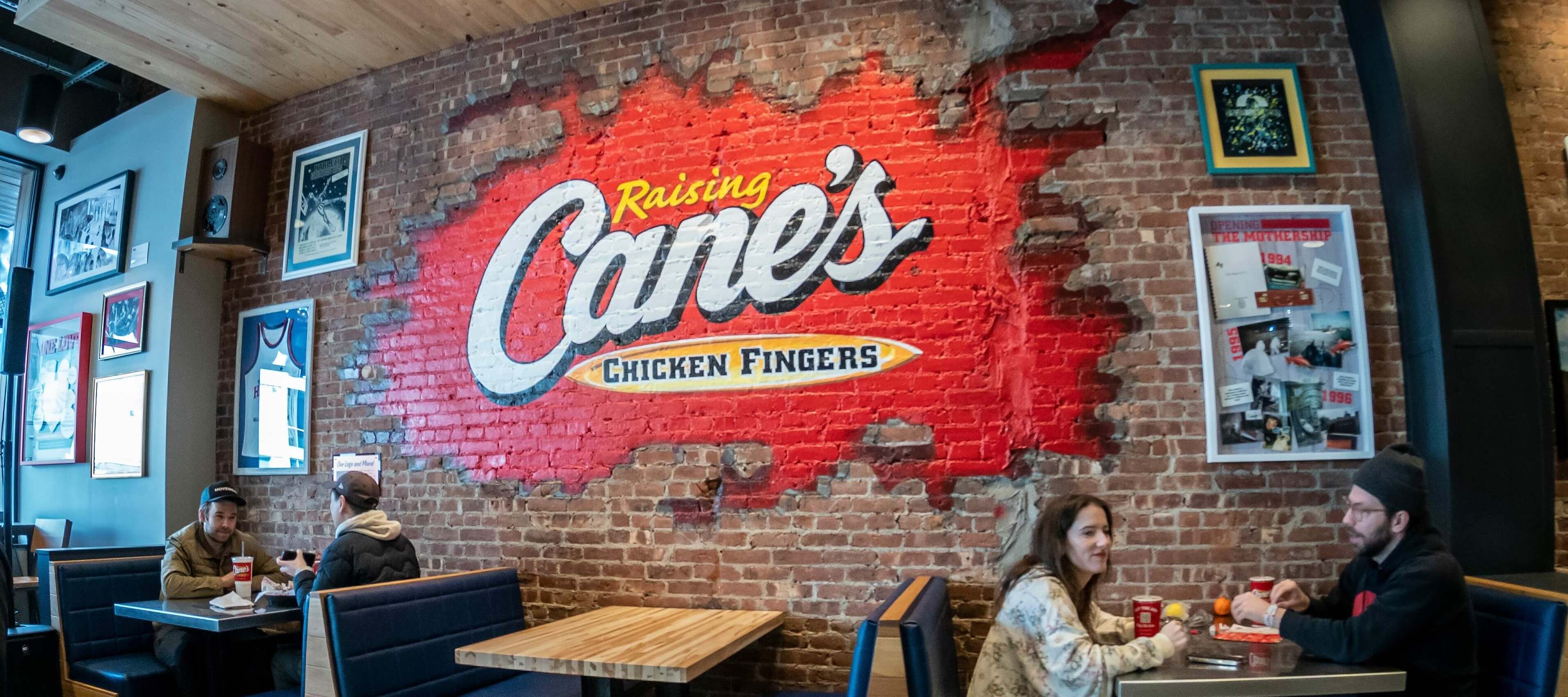 Patrons eating at a Raising Cane's, known for its fried chicken fingers.