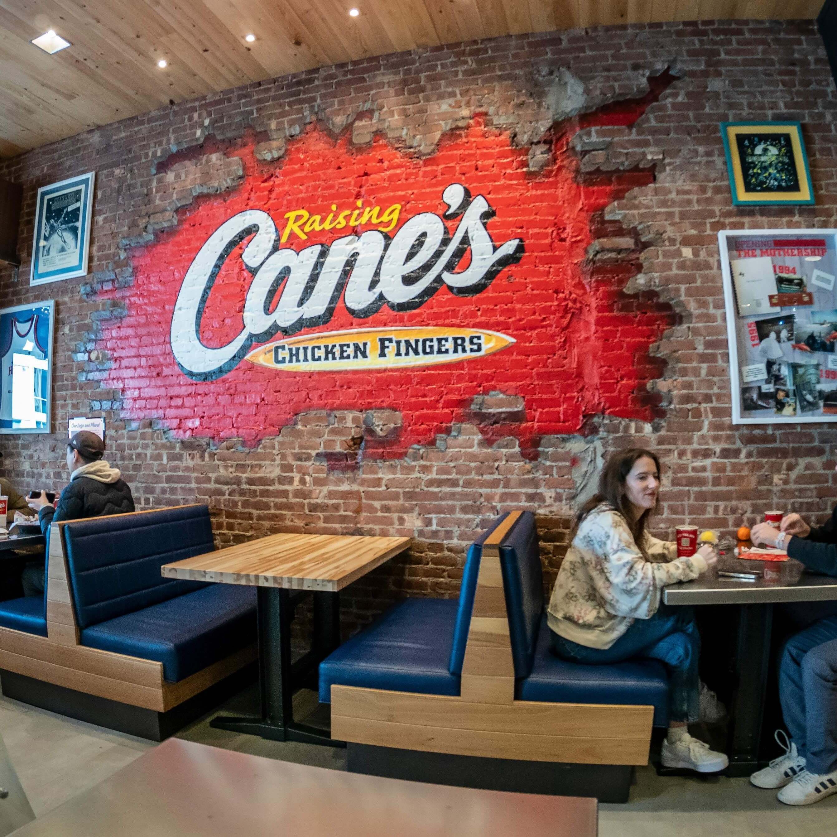 Patrons eating at a Raising Cane's, known for its fried chicken fingers.