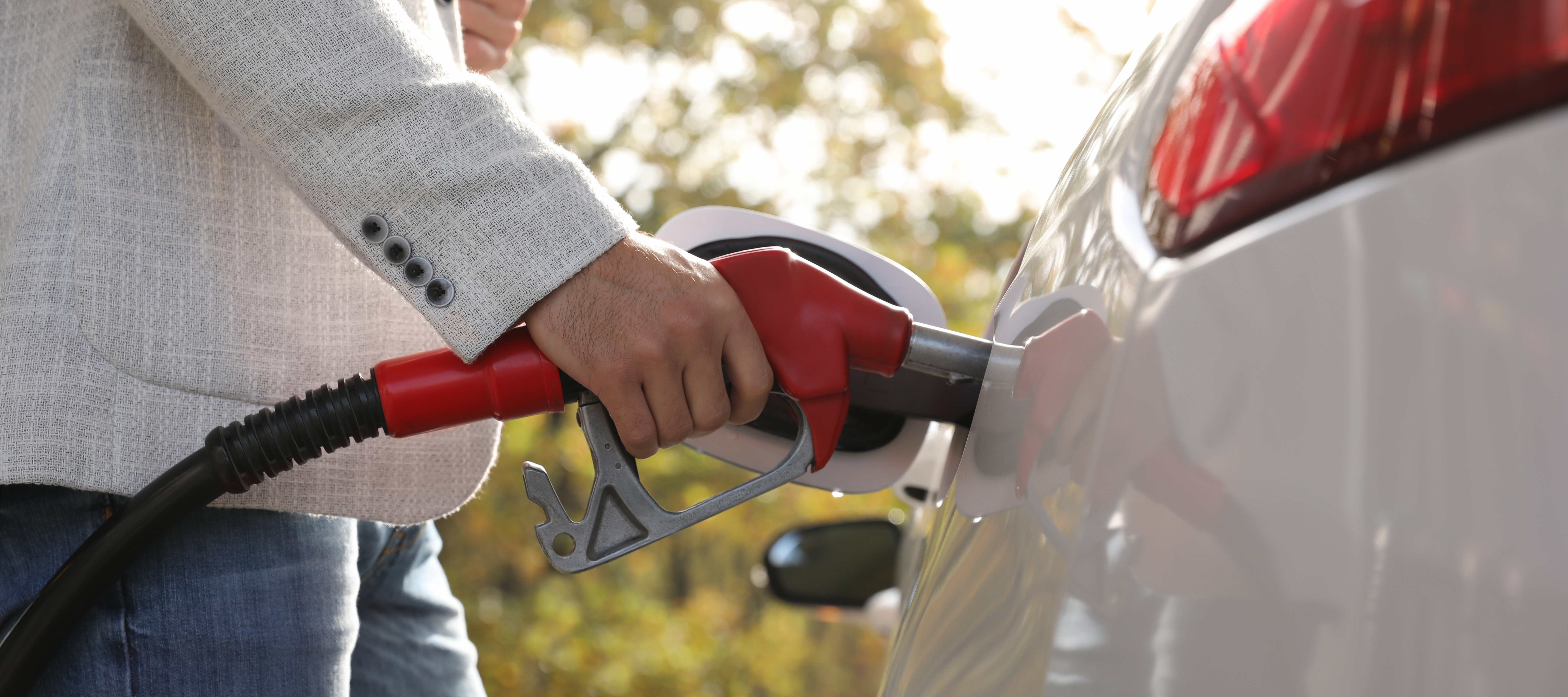 Close up of a person fueling up their car with a gas pump.