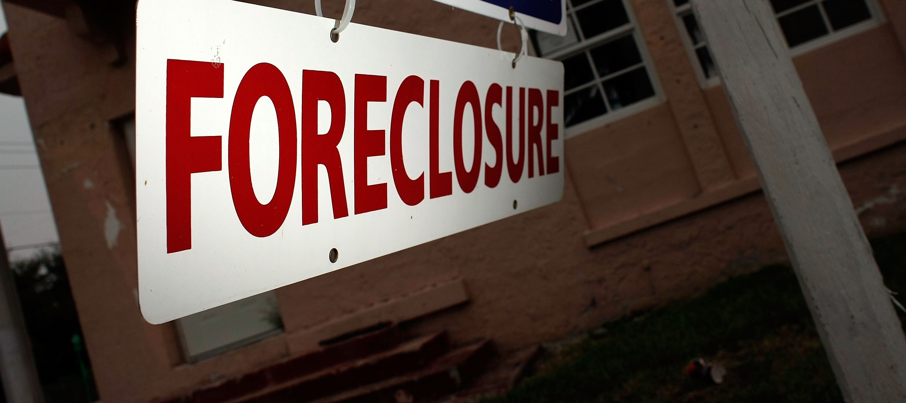 A foreclosure sign hangs in front of a building.