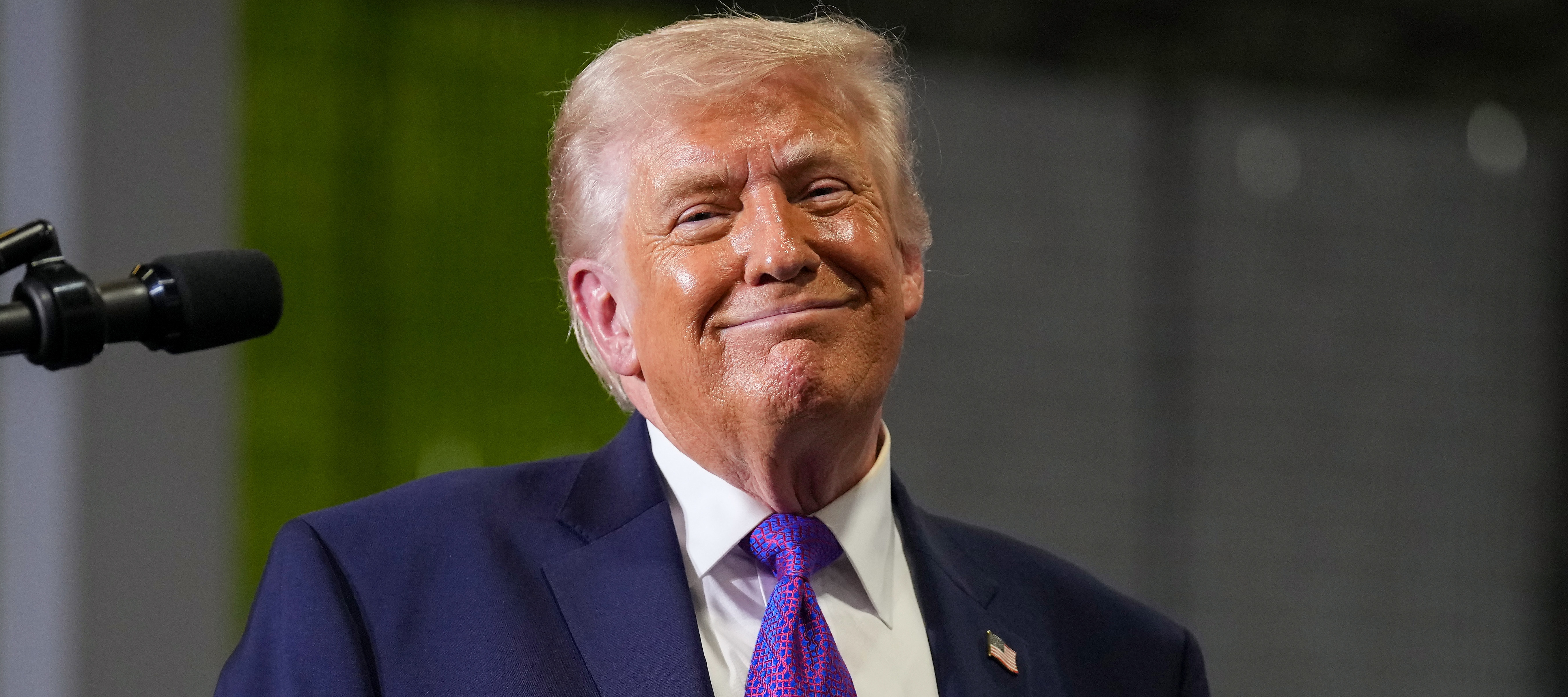 A photo of President Donald Trump smiling broadly and wearing a purple tie.