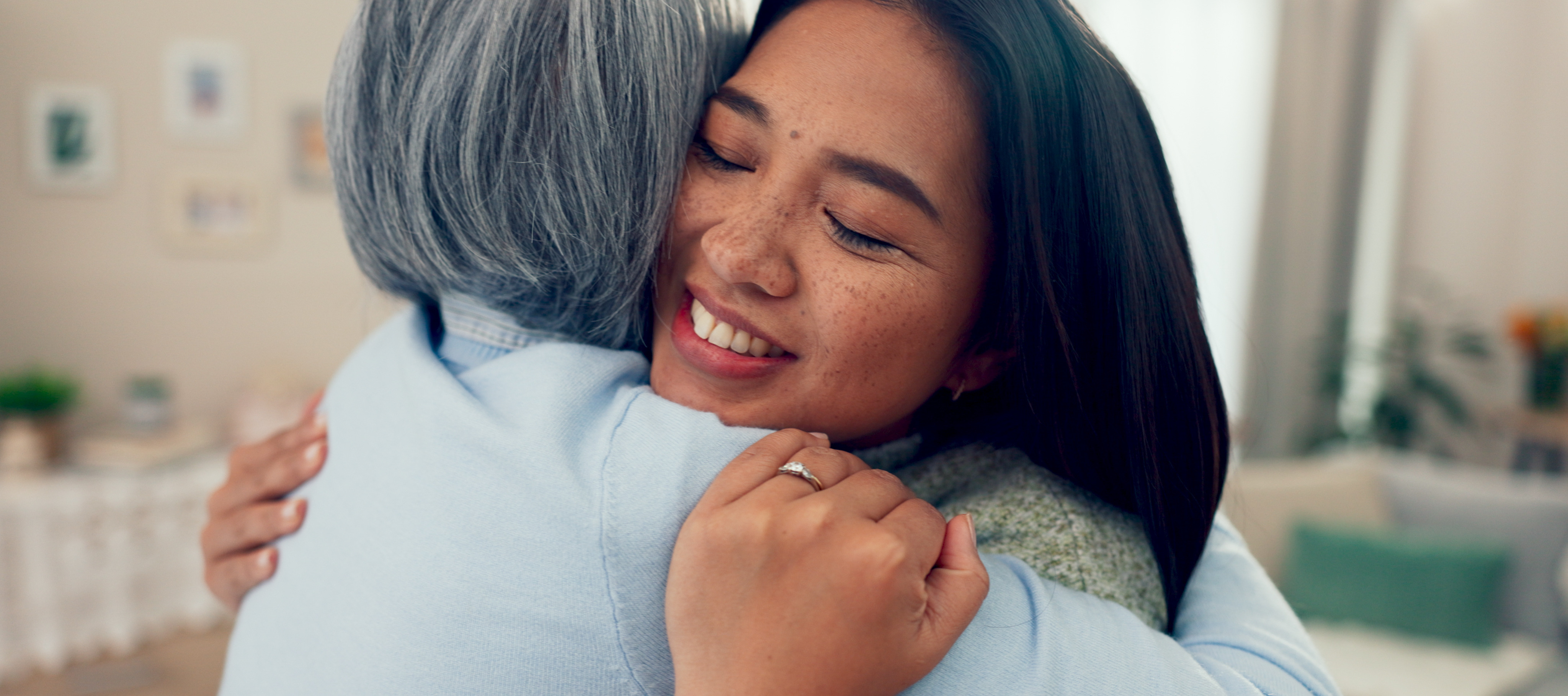 A middle-aged woman hugs her mother at home.