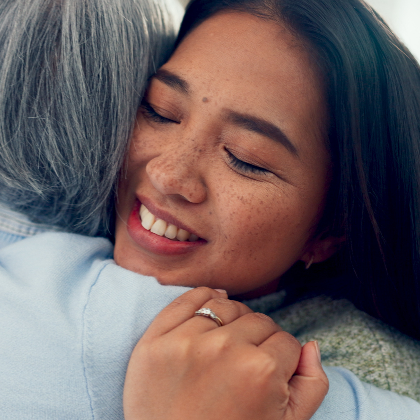 A middle-aged woman hugs her mother at home.