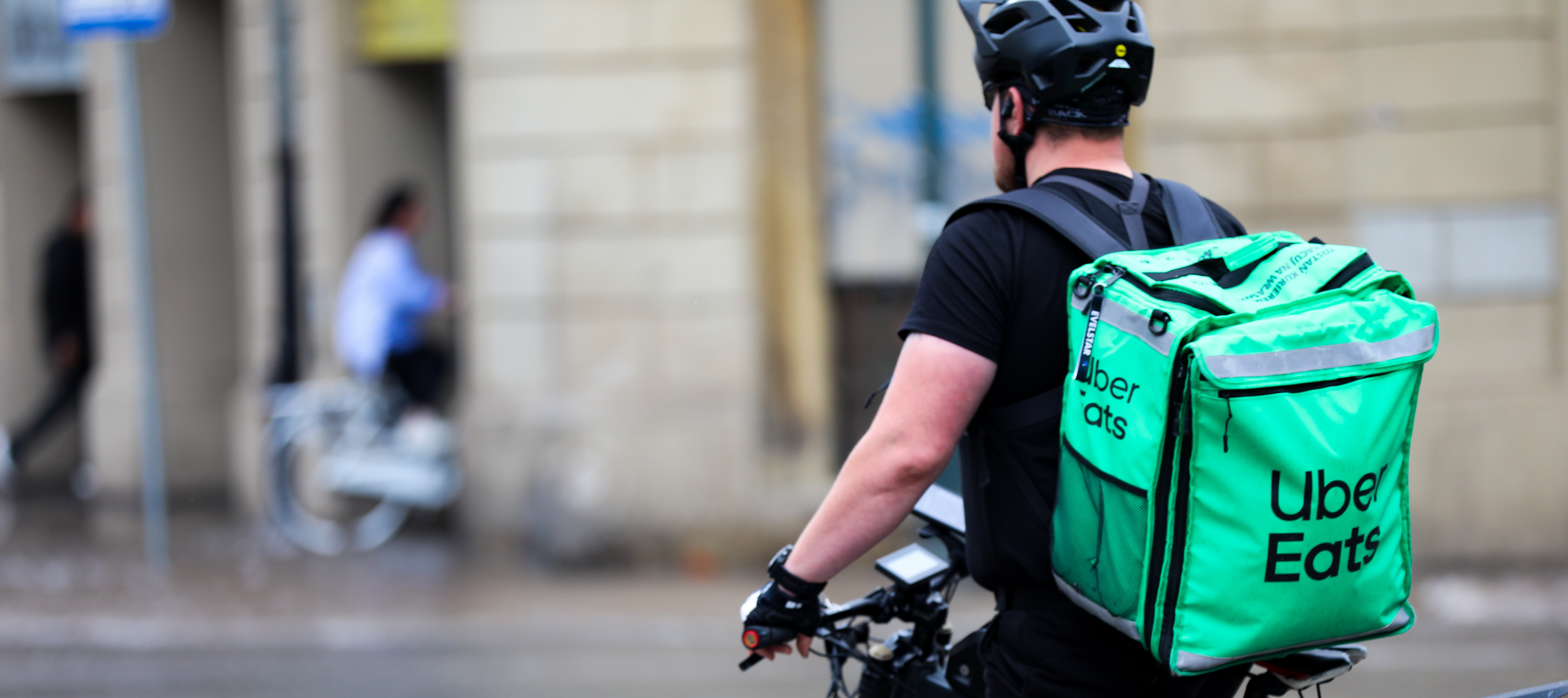 An Uber Eats delivery worker rests on his bike.