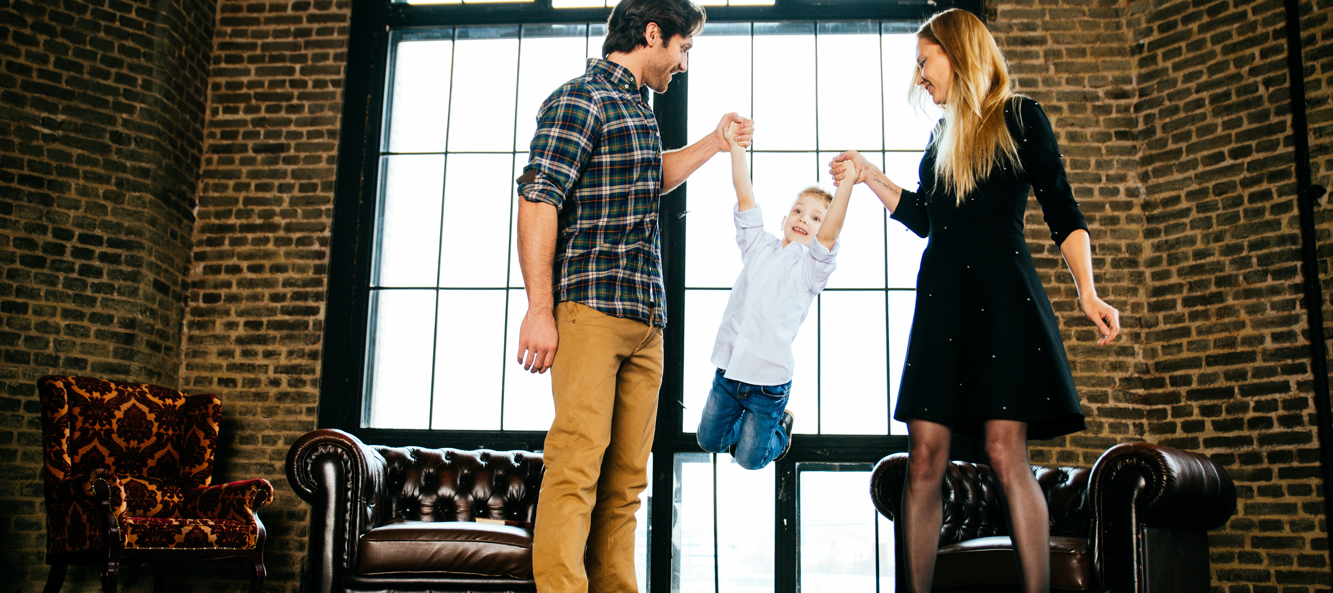A mother and father play with their son inside their home.