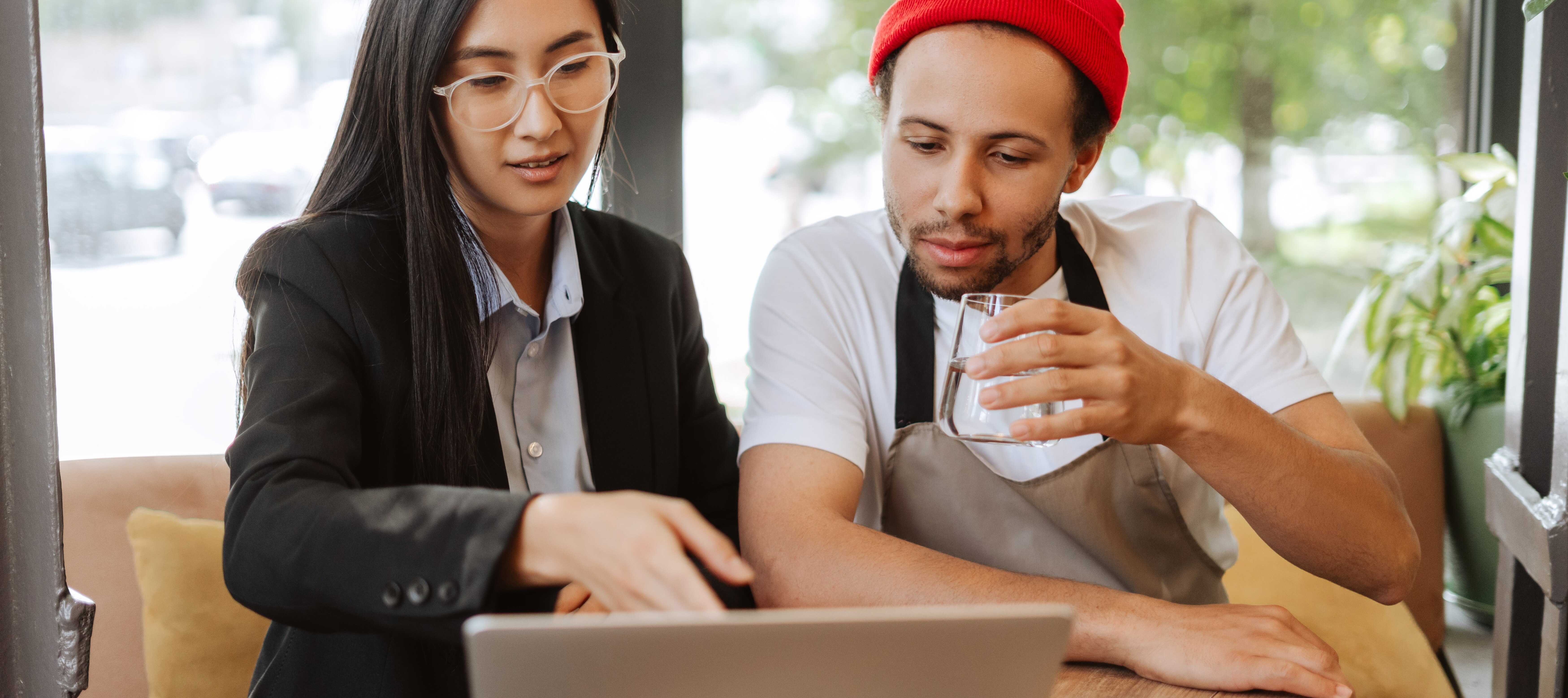 A waiter looking at a laptop with a tax professional, discussing deduction limit changes for earned tips.