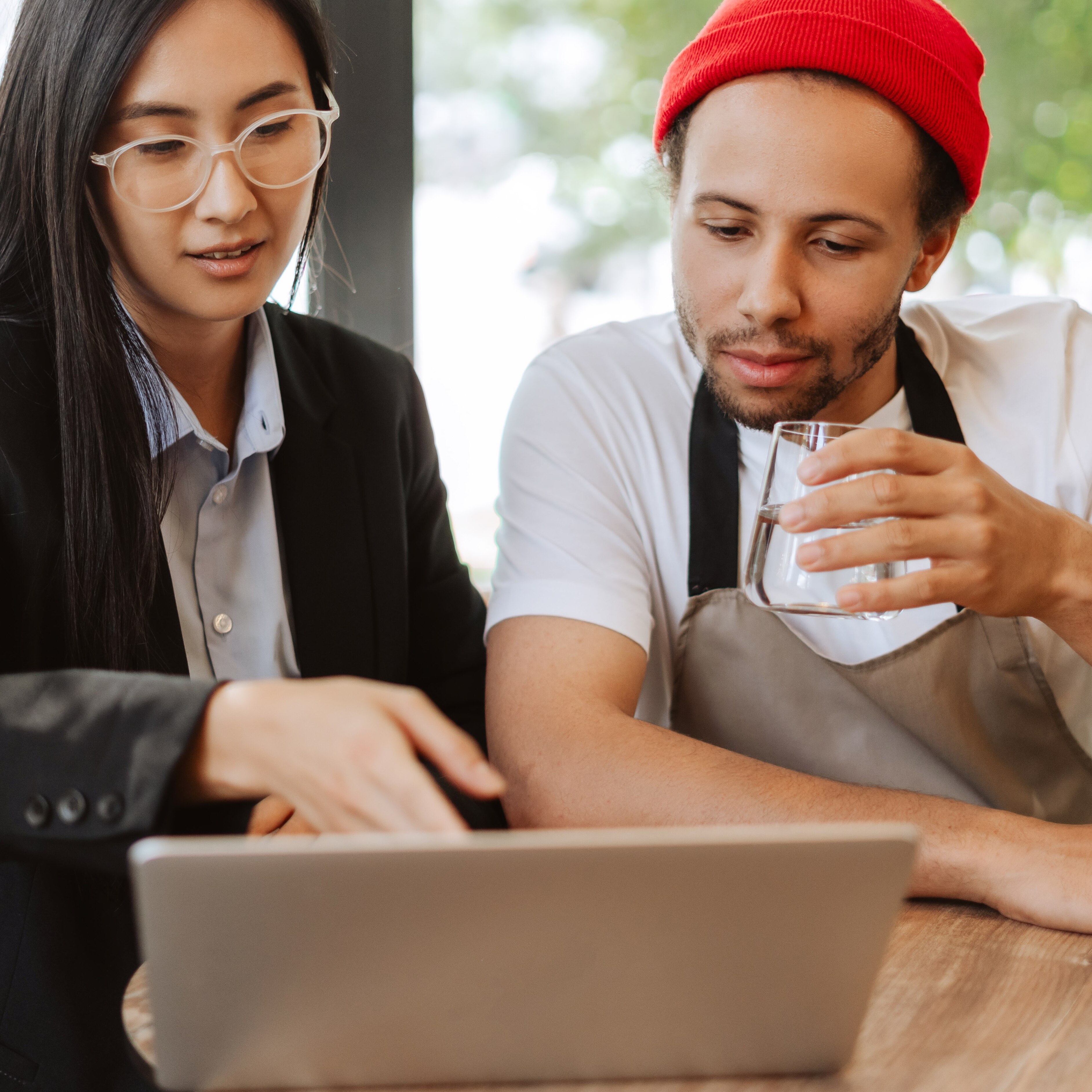 A waiter looking at a laptop with a tax professional, discussing deduction limit changes for earned tips.