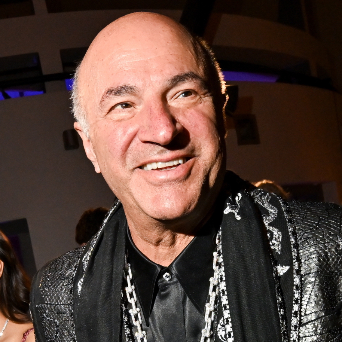 A composition image of Kevin O'Leary in a black and silver suit on the left, and a close-up of his white gold and ruby encrusted NBA necklace on the right.