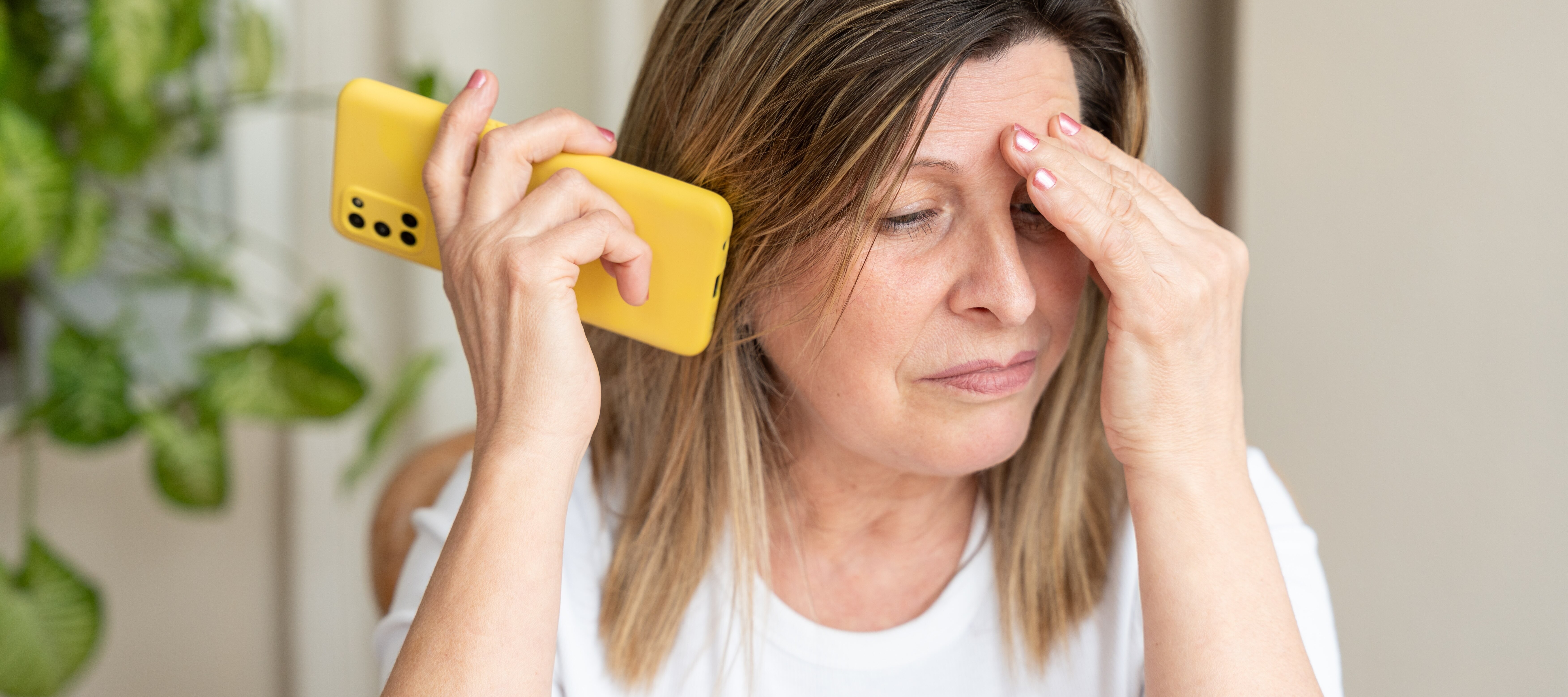 Middle aged woman looking stressed discussing a scam on the phone.