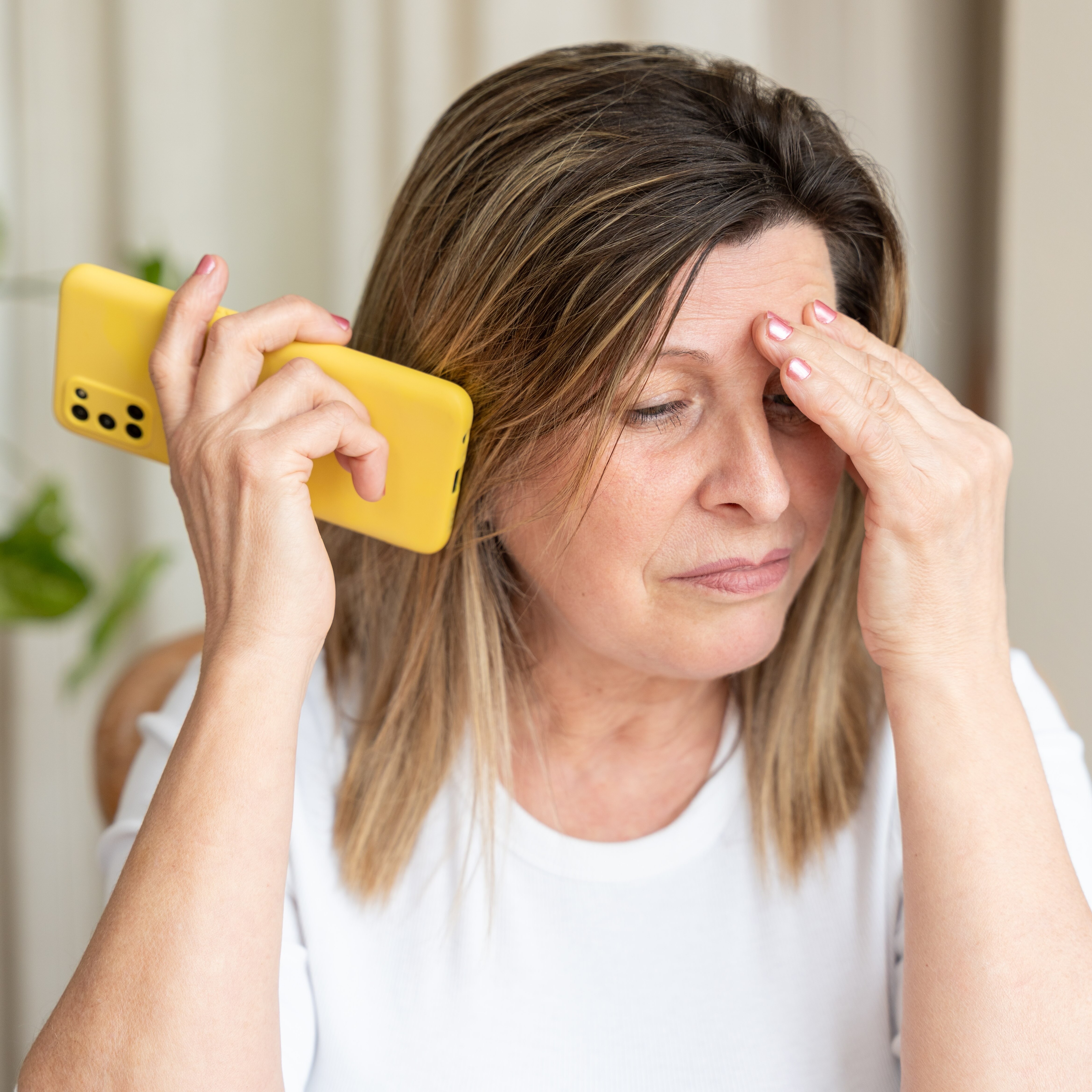 Middle aged woman looking stressed discussing a scam on the phone.