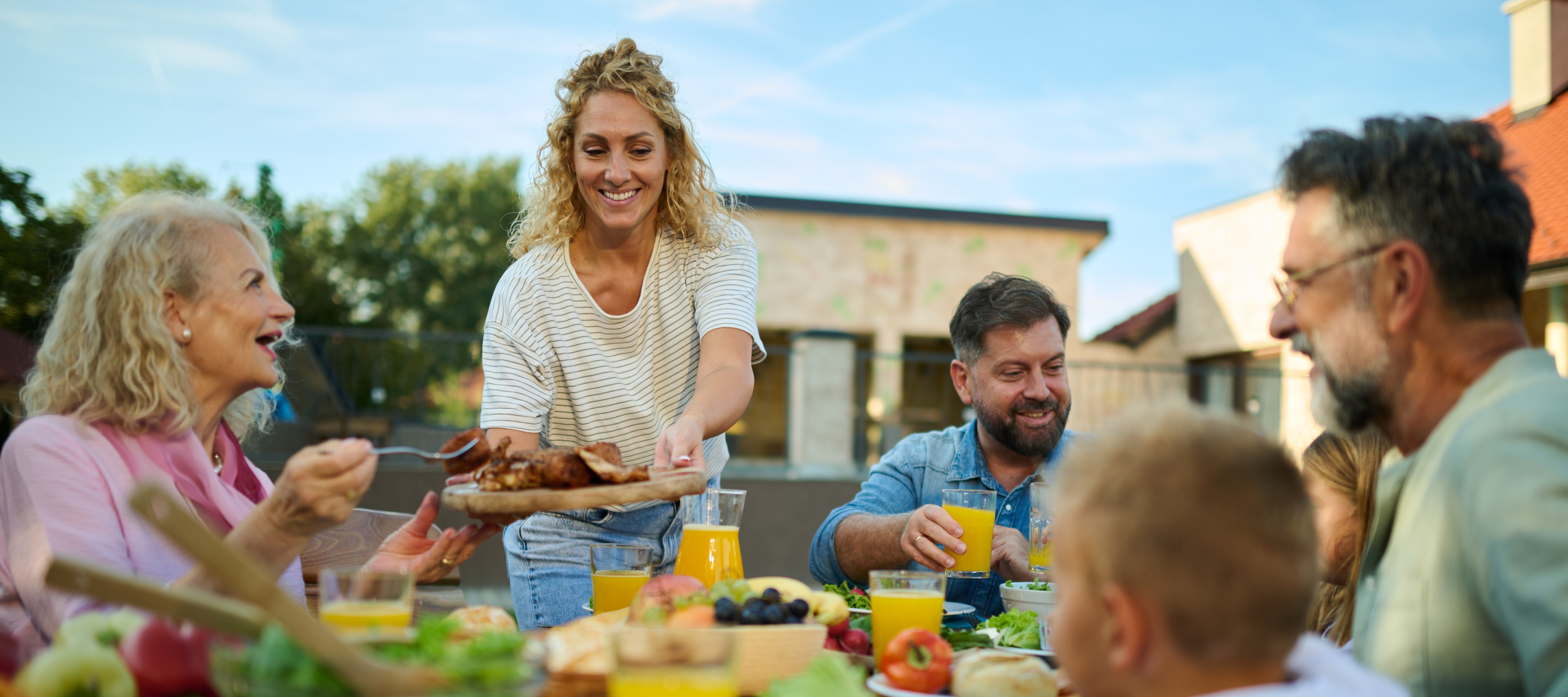 A multigenerational family enjoys lunch together in their backyard.