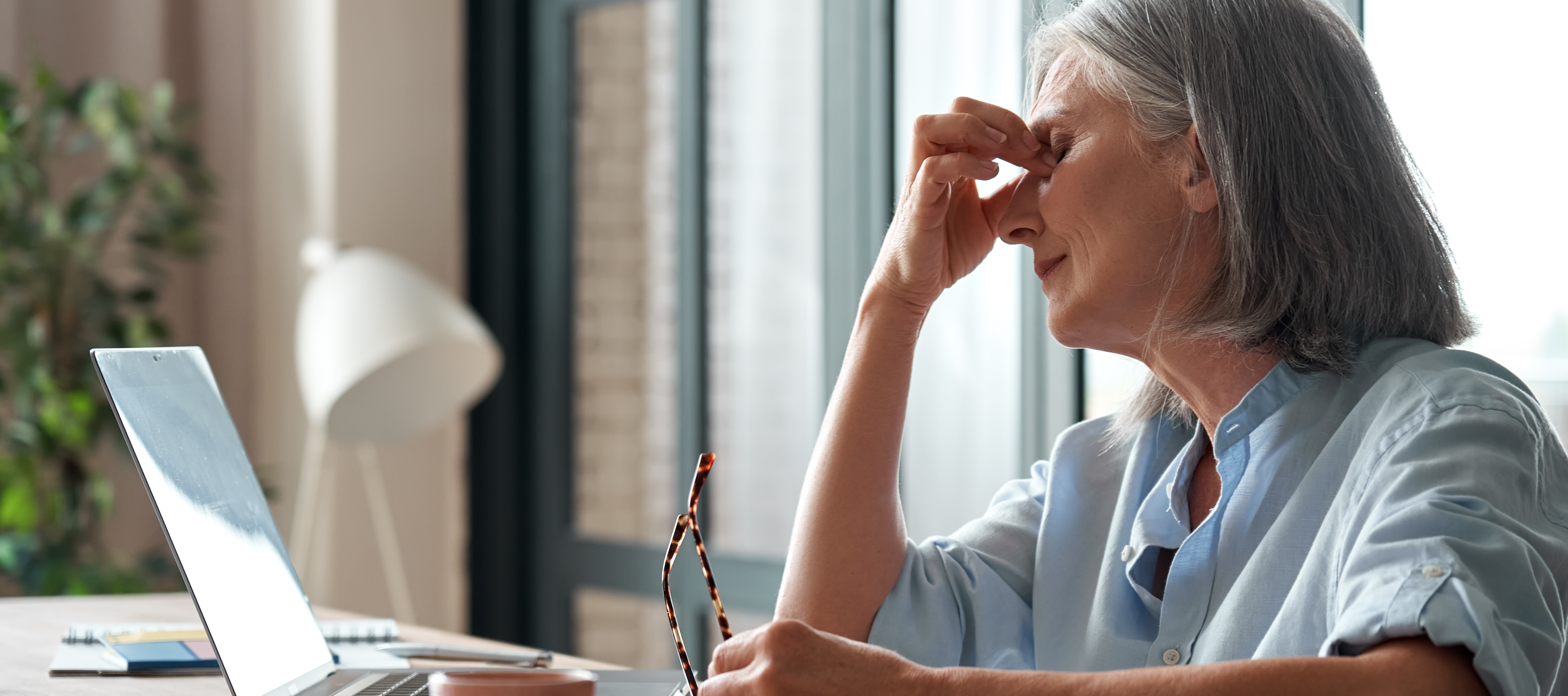 Senior business woman suffering from eyestrain, stress, headache, fatigue after computer work in office.