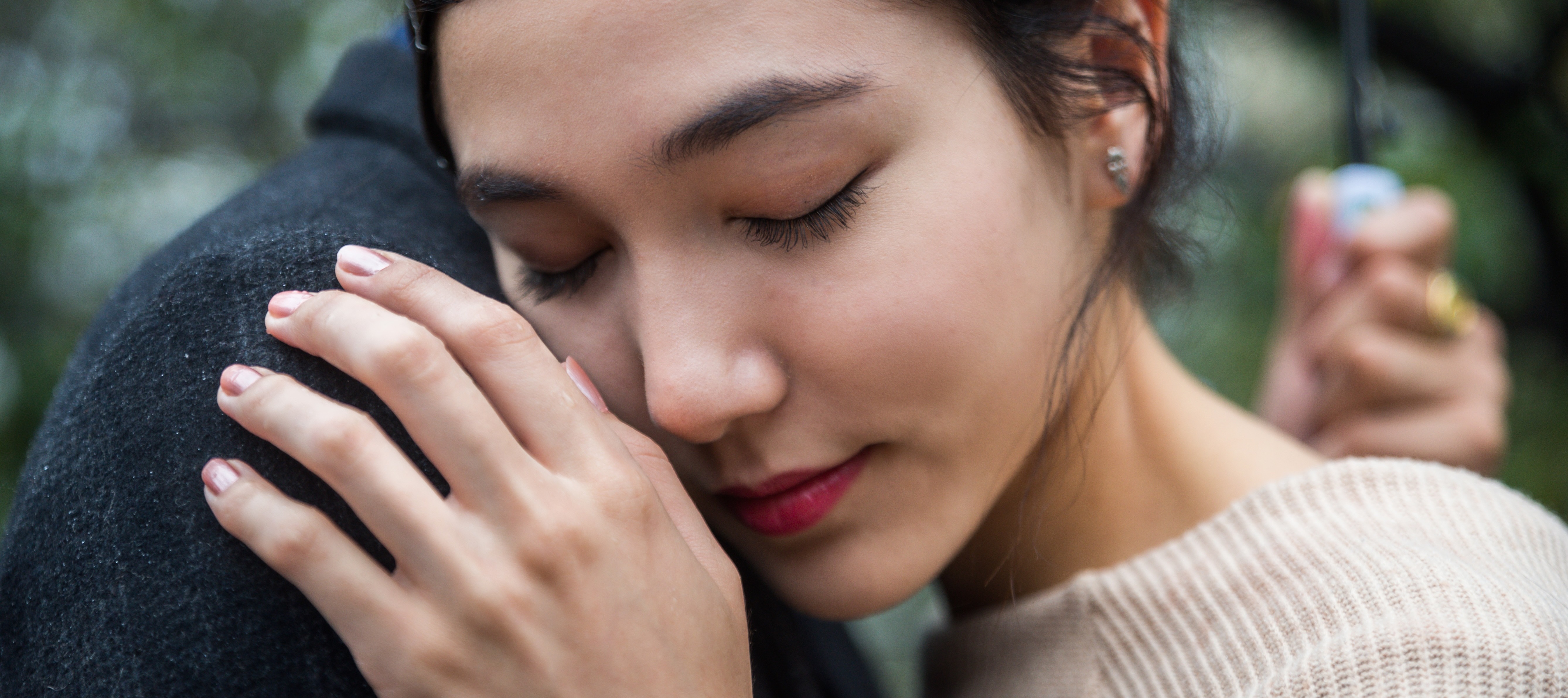 A close-up of a young woman embracing someone in the rain.
