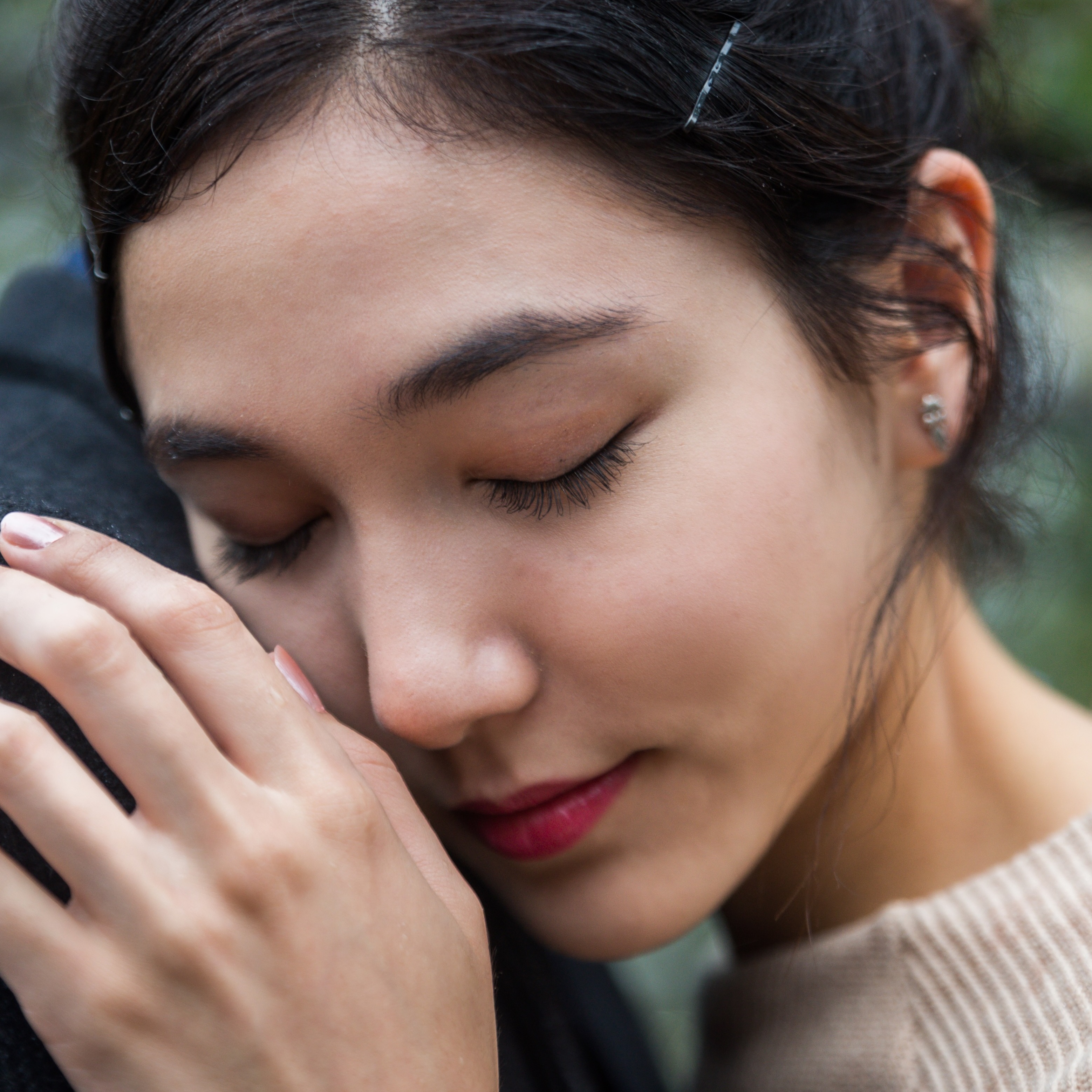 A close-up of a young woman embracing someone in the rain.