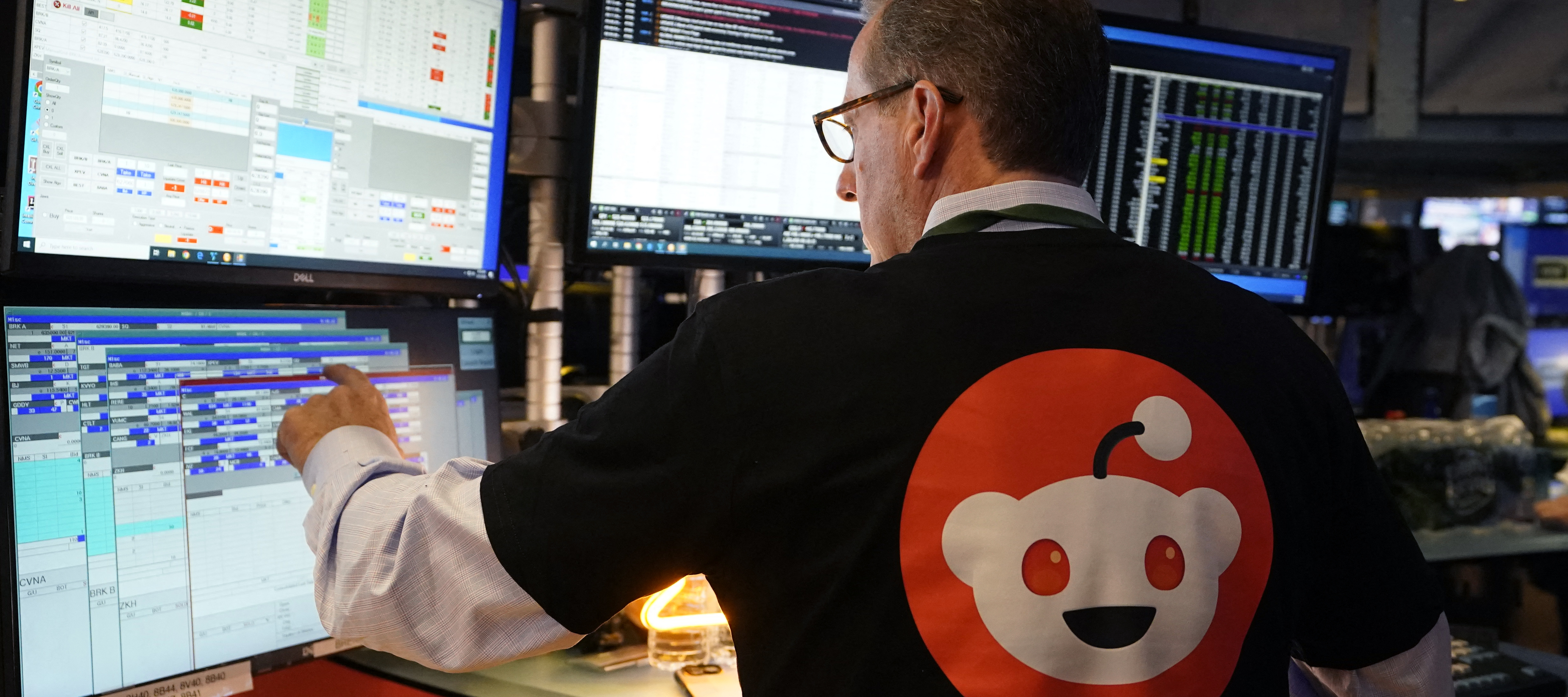 A Wall Street trader wearing a Reddit t-shirt works at his console.