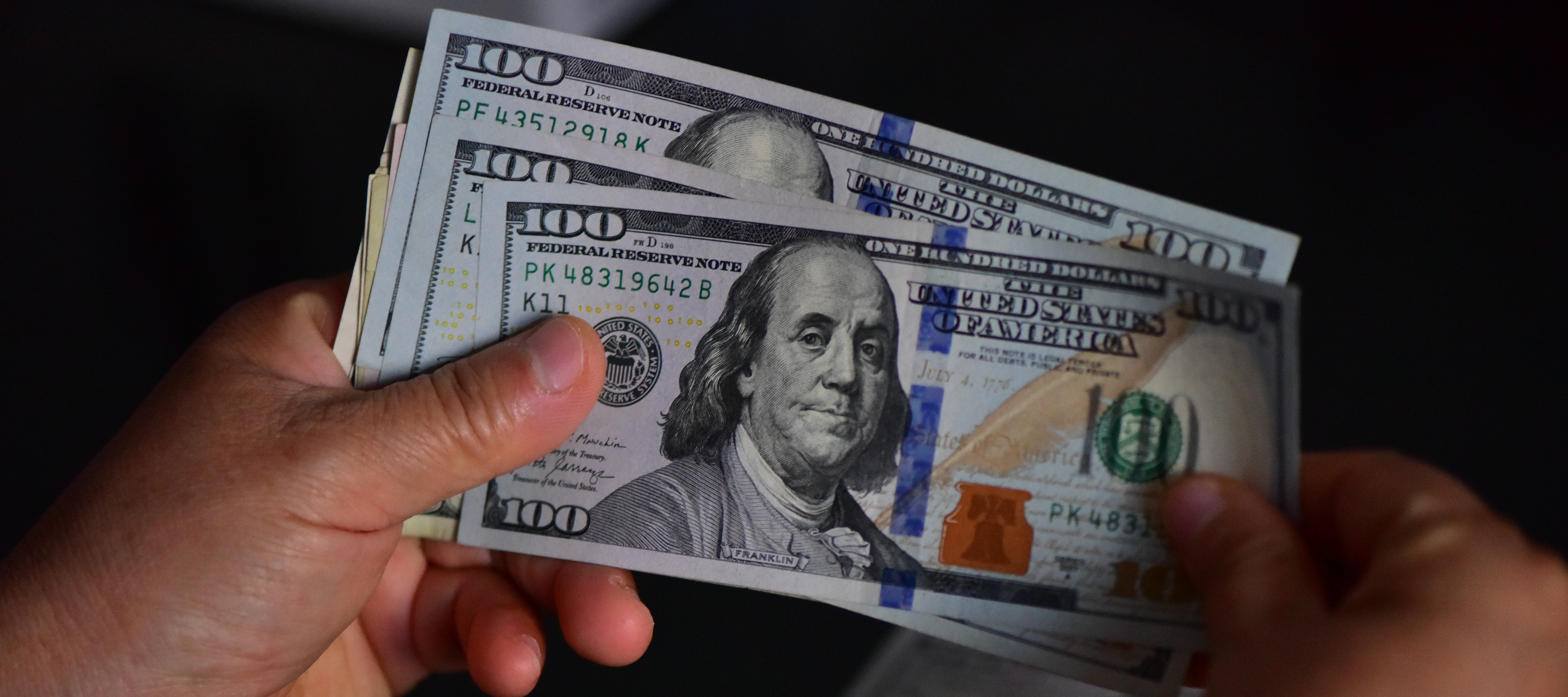 Someone thumbs through a stack of $100 bills.