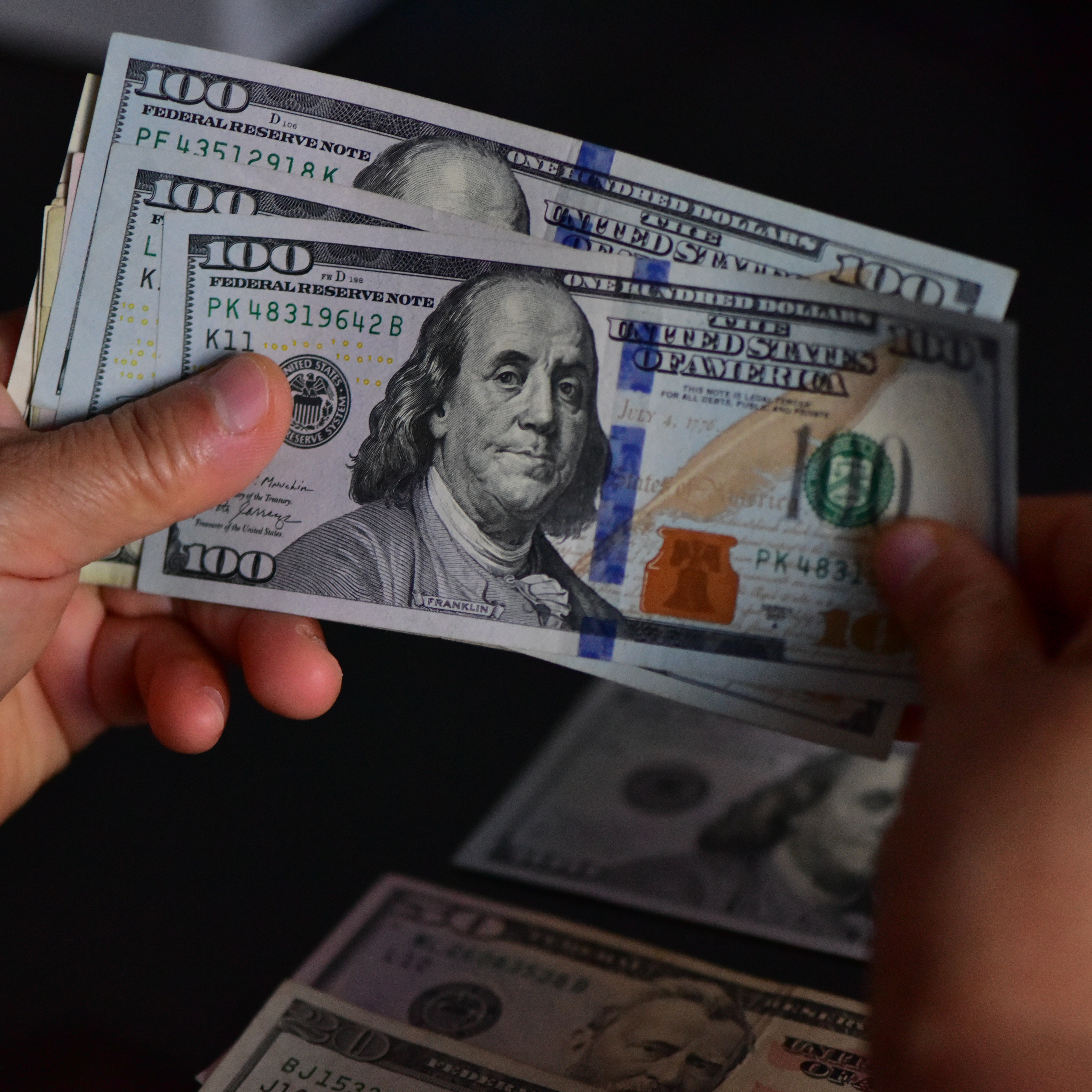Someone thumbs through a stack of $100 bills.
