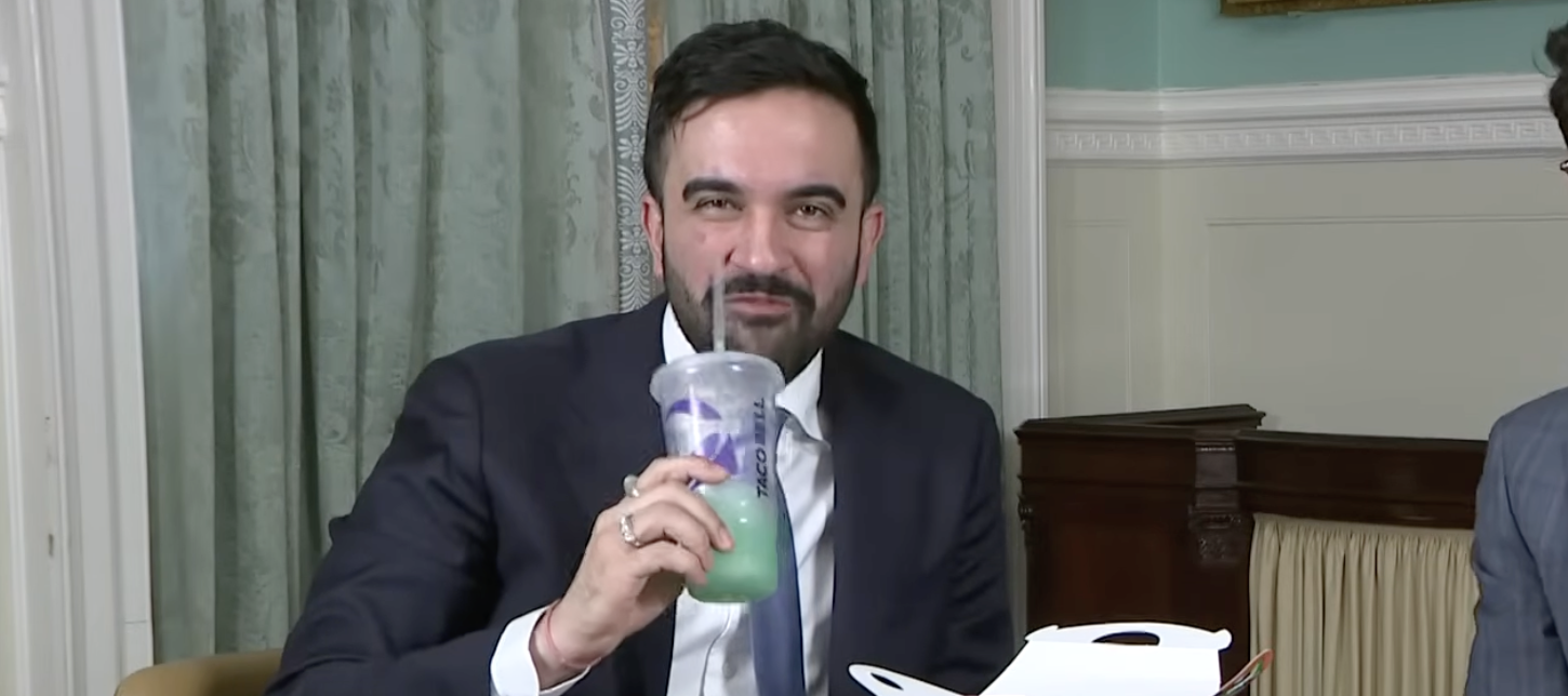 An image of NYC Mayor Zohran Mamdani eating Taco Bell while talking about the $1.8M his administration won for fast food workers.