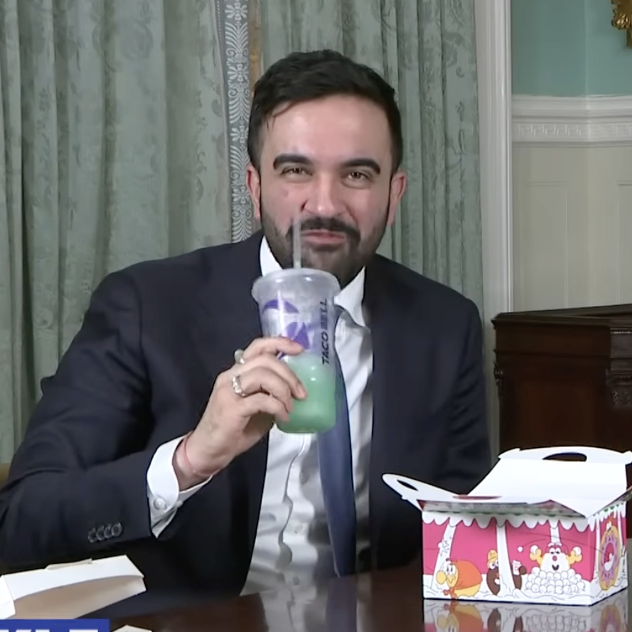 An image of NYC Mayor Zohran Mamdani eating Taco Bell while talking about the $1.8M his administration won for fast food workers.