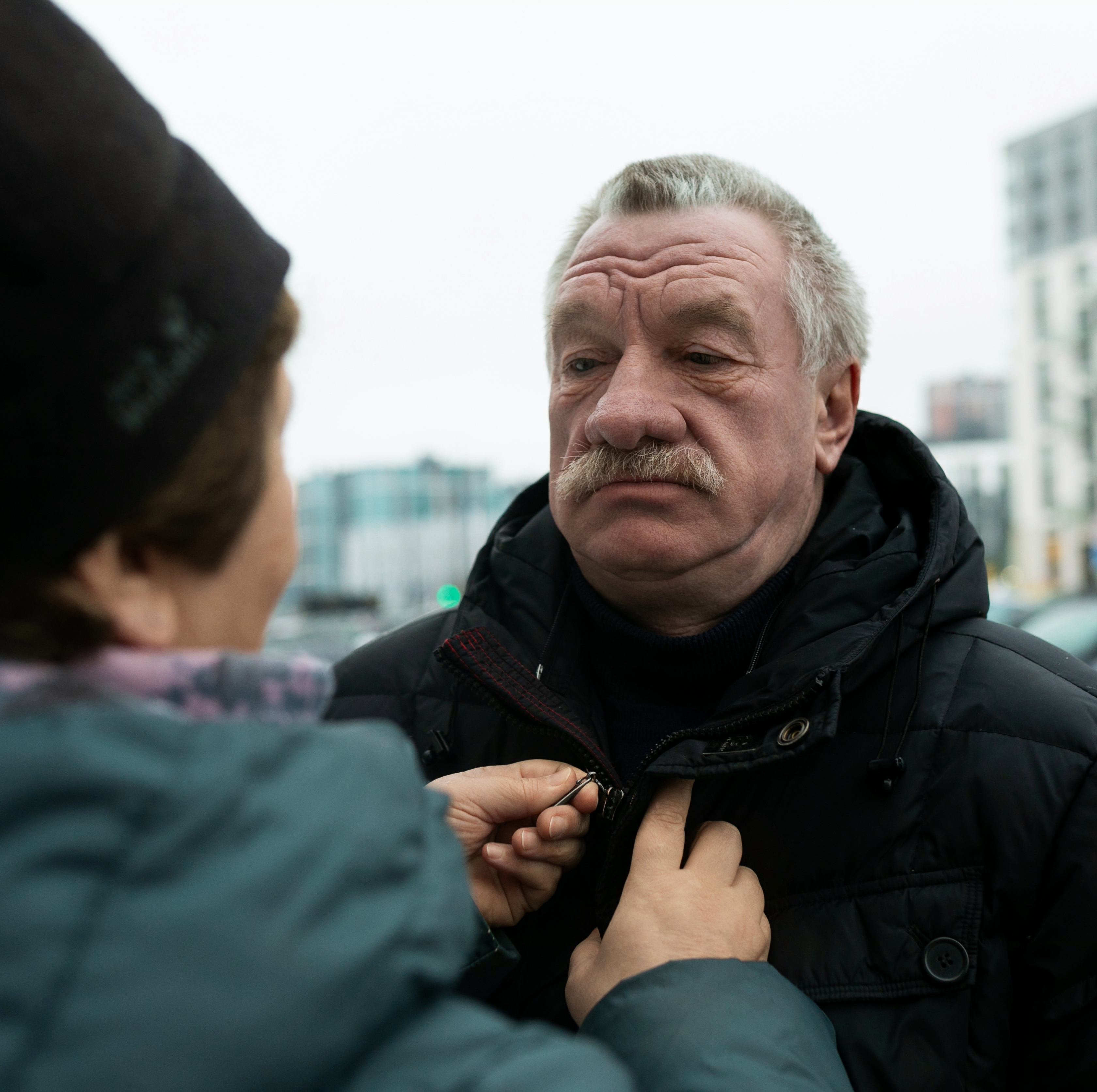 Couple in their 50s pictured as wife zips up husband's winter jacket.
