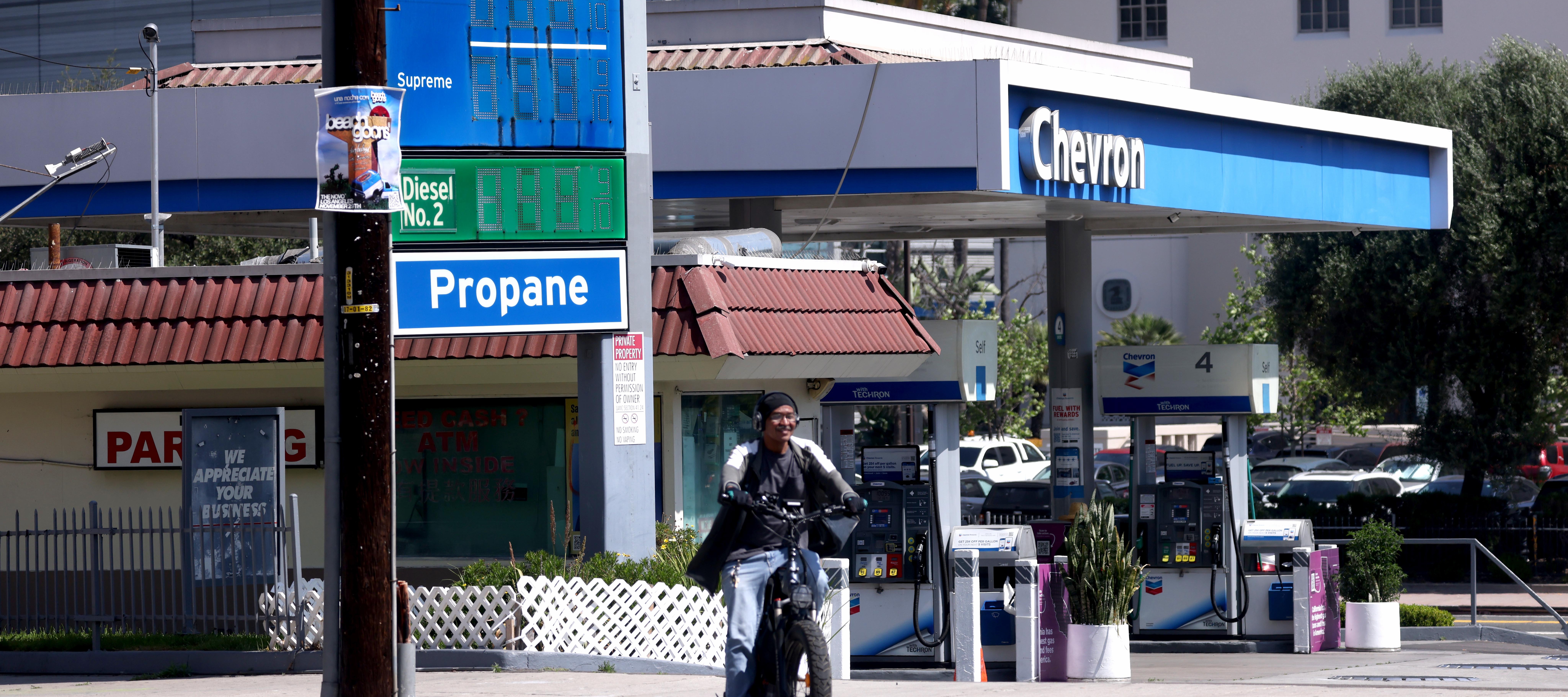 A cyclist rides by a Chevron Station in Los Angeles, weeks after the company said it may pull its oil refinery operations out of the state.