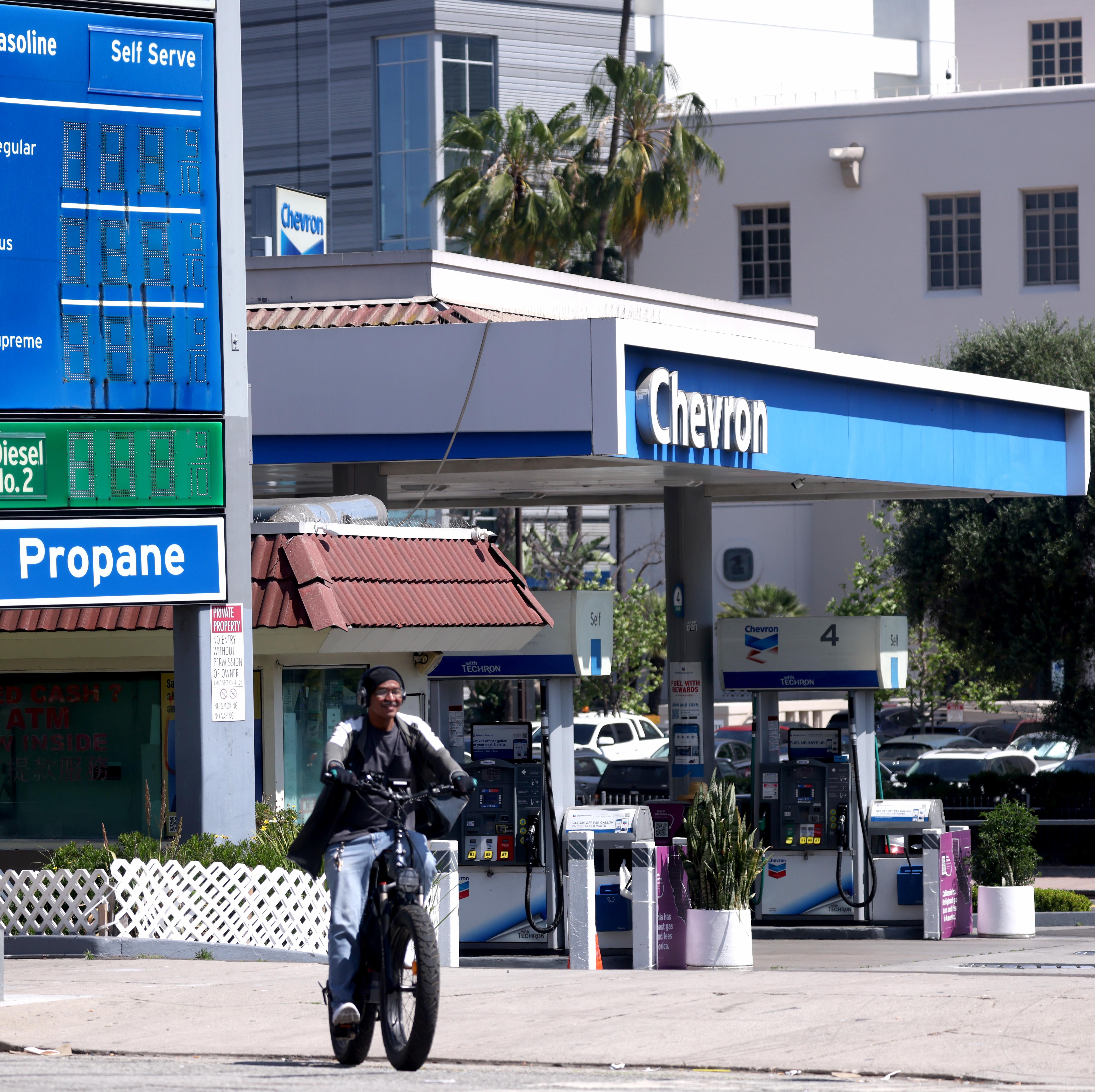 A cyclist rides by a Chevron Station in Los Angeles, weeks after the company said it may pull its oil refinery operations out of the state.