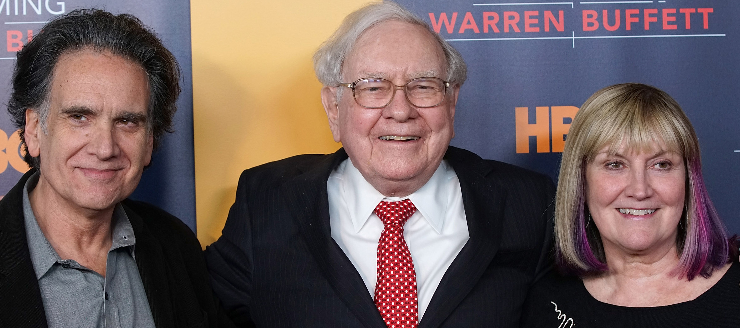 Warren Buffett smiles broadly, hands around the shoulders two of his children: Peter and Susie.