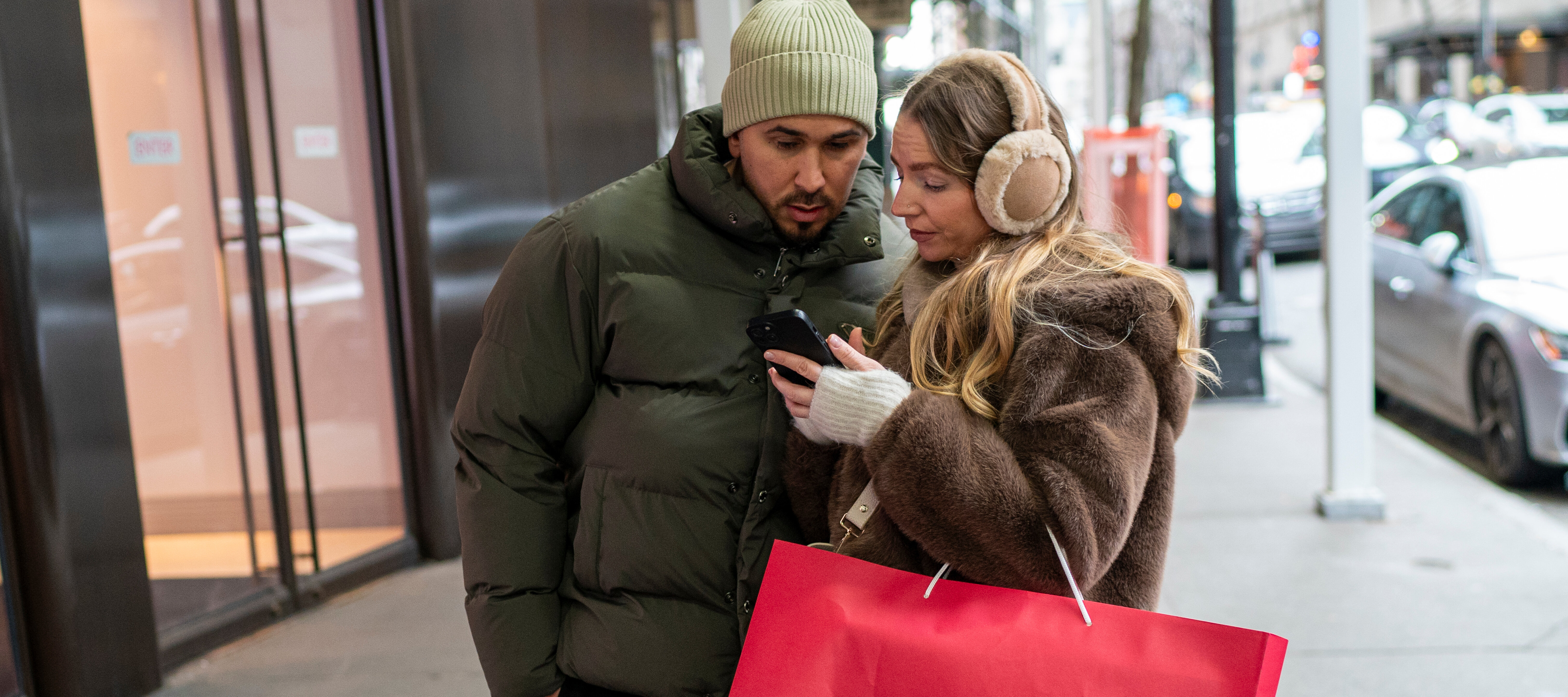 Two shoppers glance at one of their mobile phones.