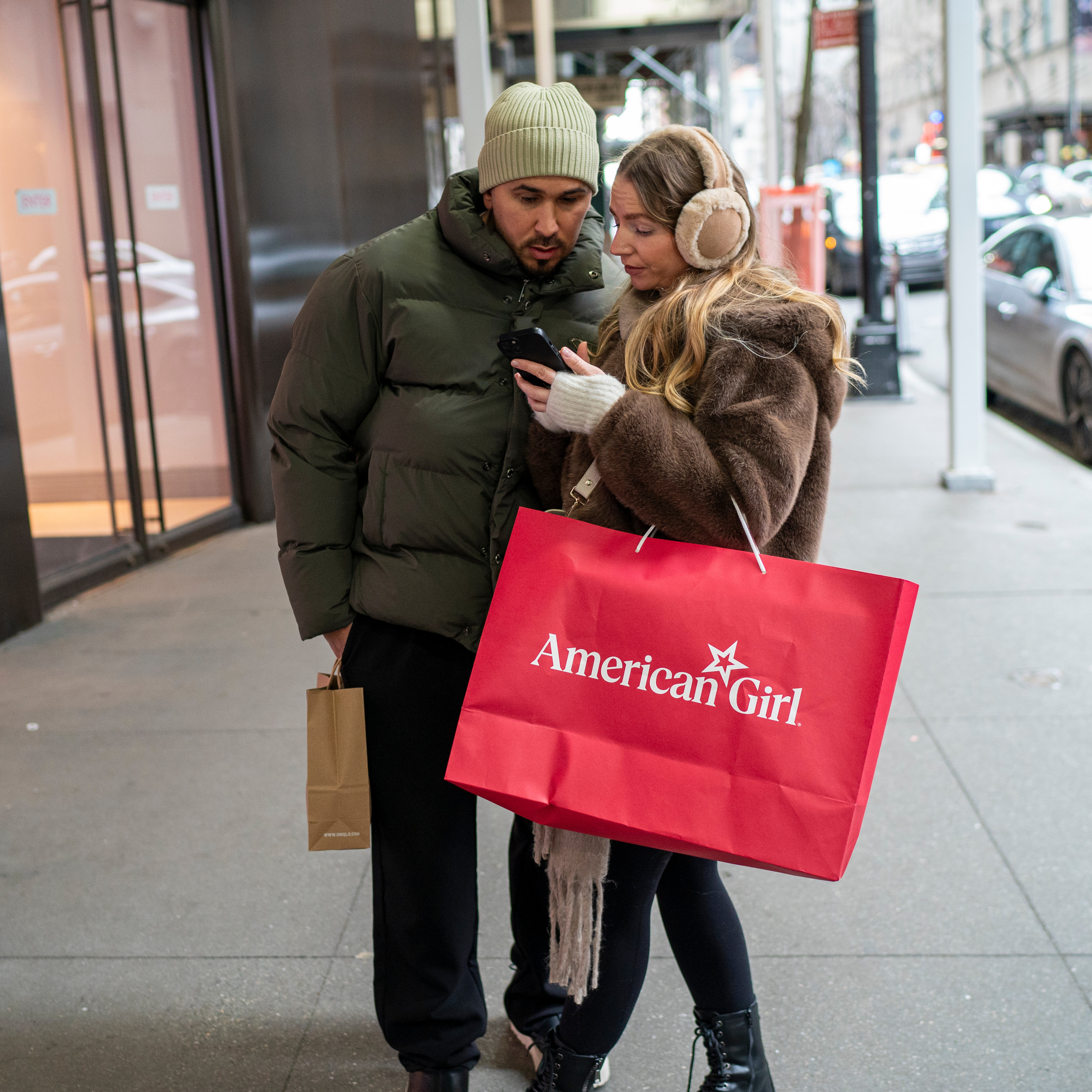 Two shoppers glance at one of their mobile phones.