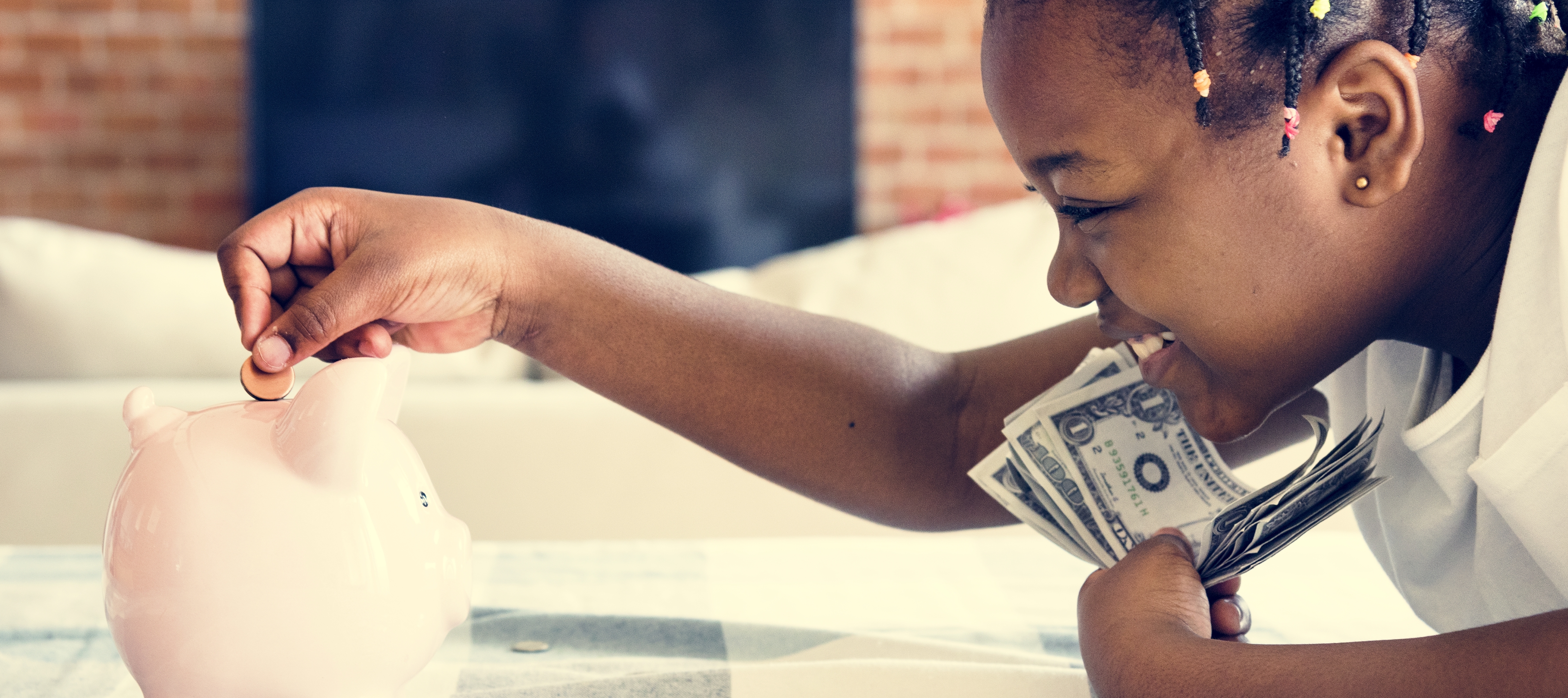 A young girl puts her coins into a piggy bank.