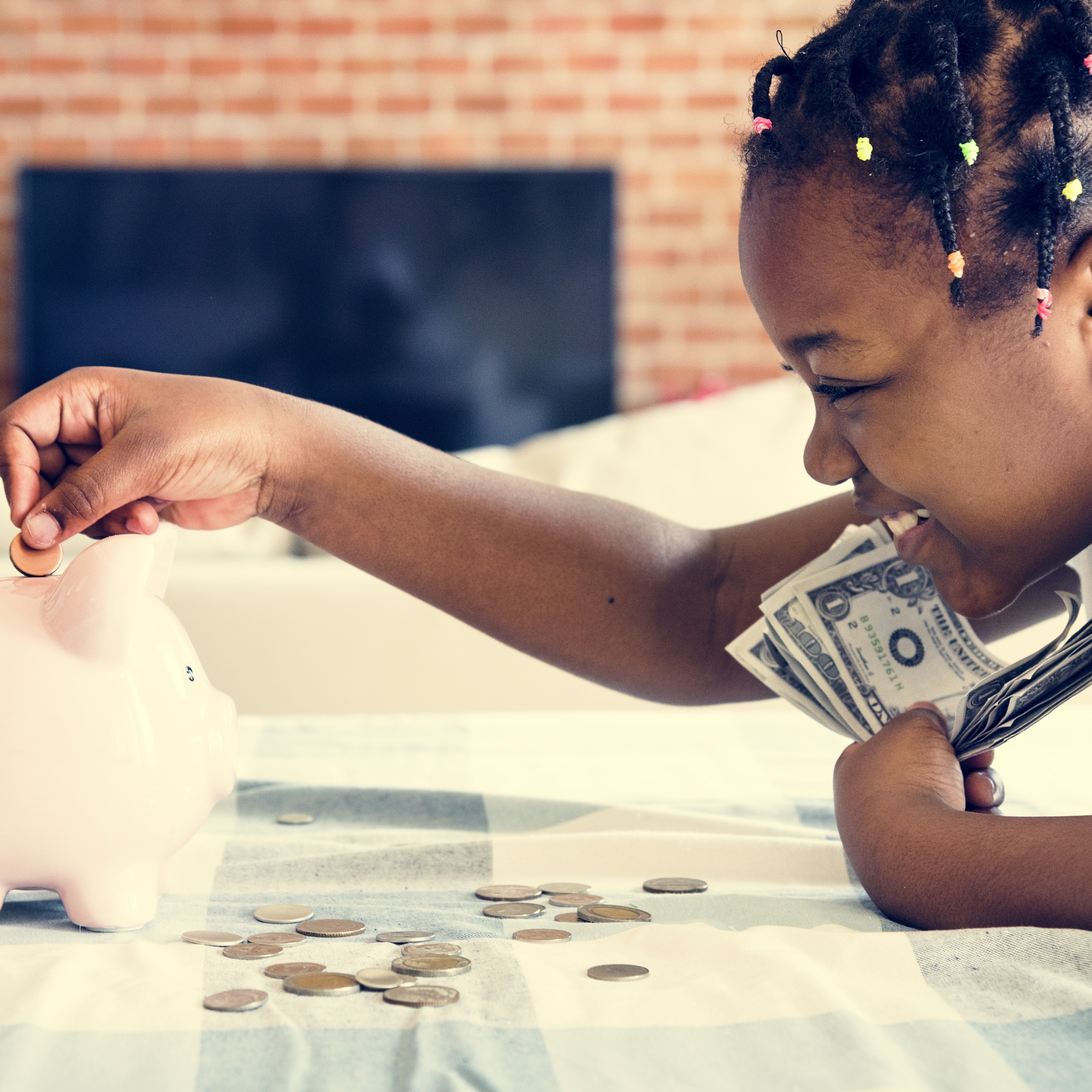A young girl puts her coins into a piggy bank.