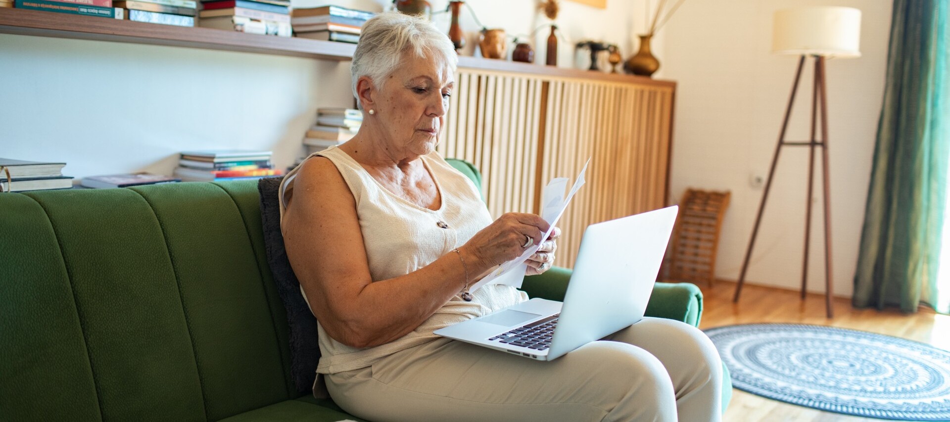 Senior woman managing bills and finances at home with laptop.