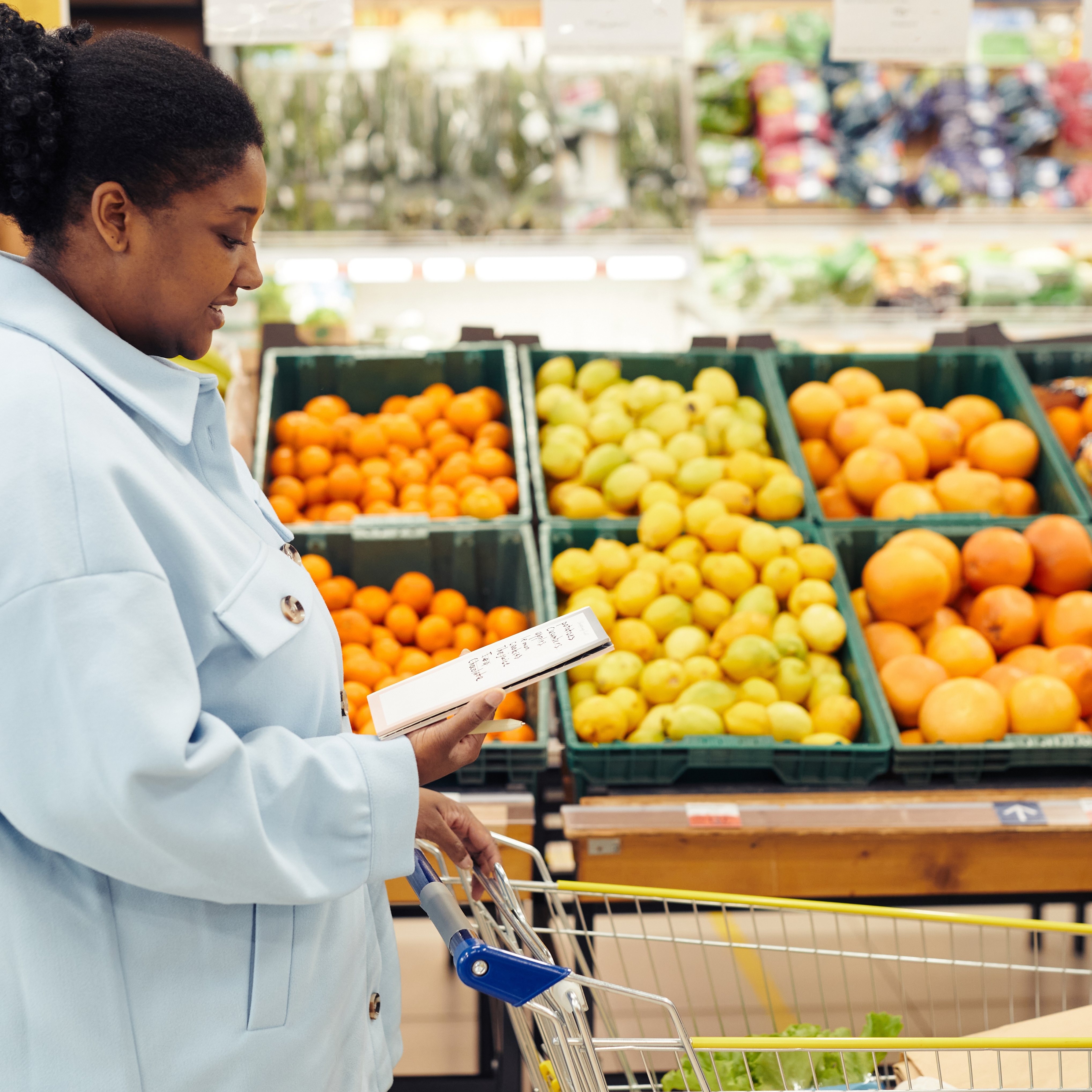 A woman looks at her grocery list as she walks down a fruit aisle, where shoppers could see price hikes as a result of the war in Iran.
