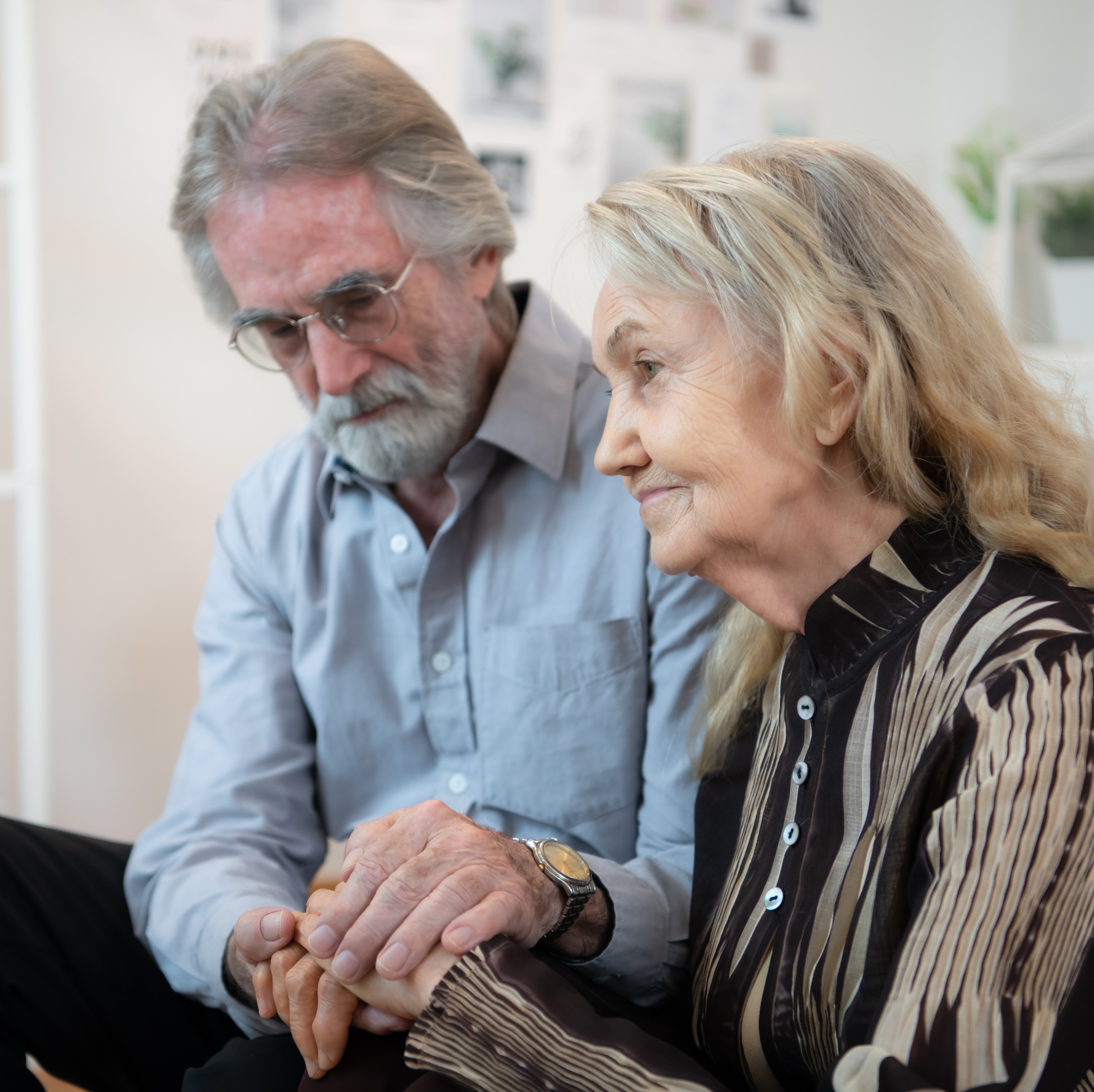 An older couple hold hands as they wait for a long term nursing care staffer to join them.