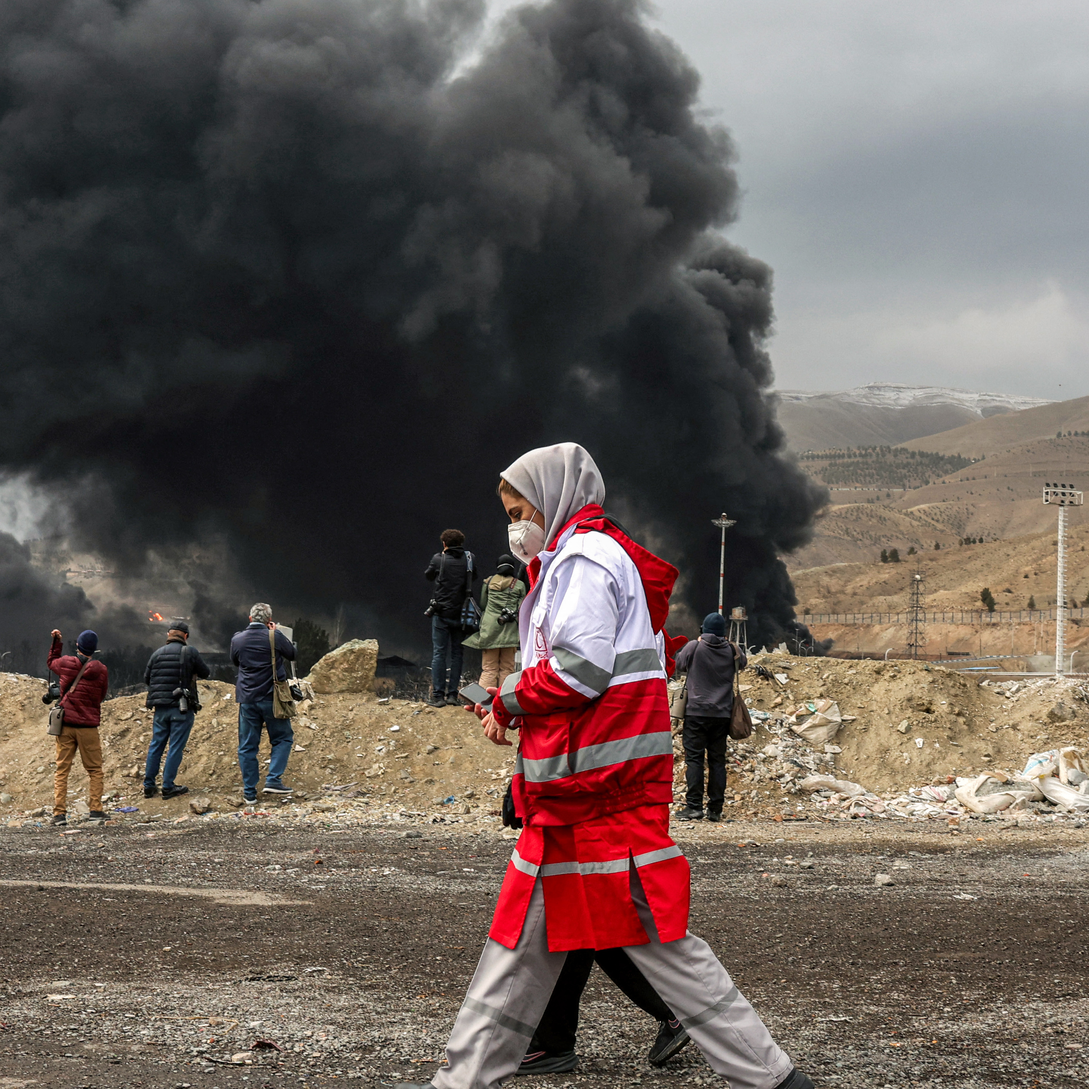 Members of Iran's Red Crescent Society walk past smoke from a fire following an airstrike on March 8, 2026, with millions of dollars being wagered on when U.S. troops will set foot in Iran.