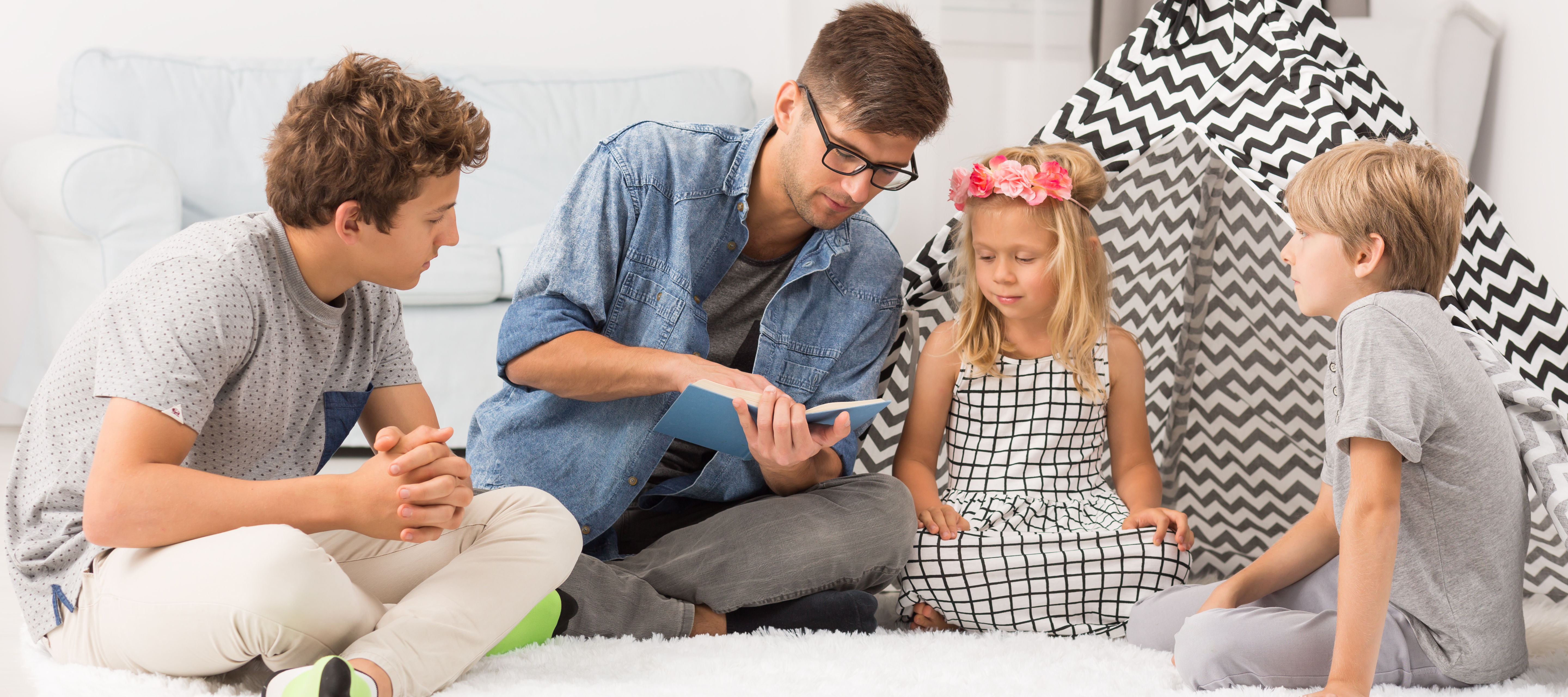 A father reads a book to three of his children.