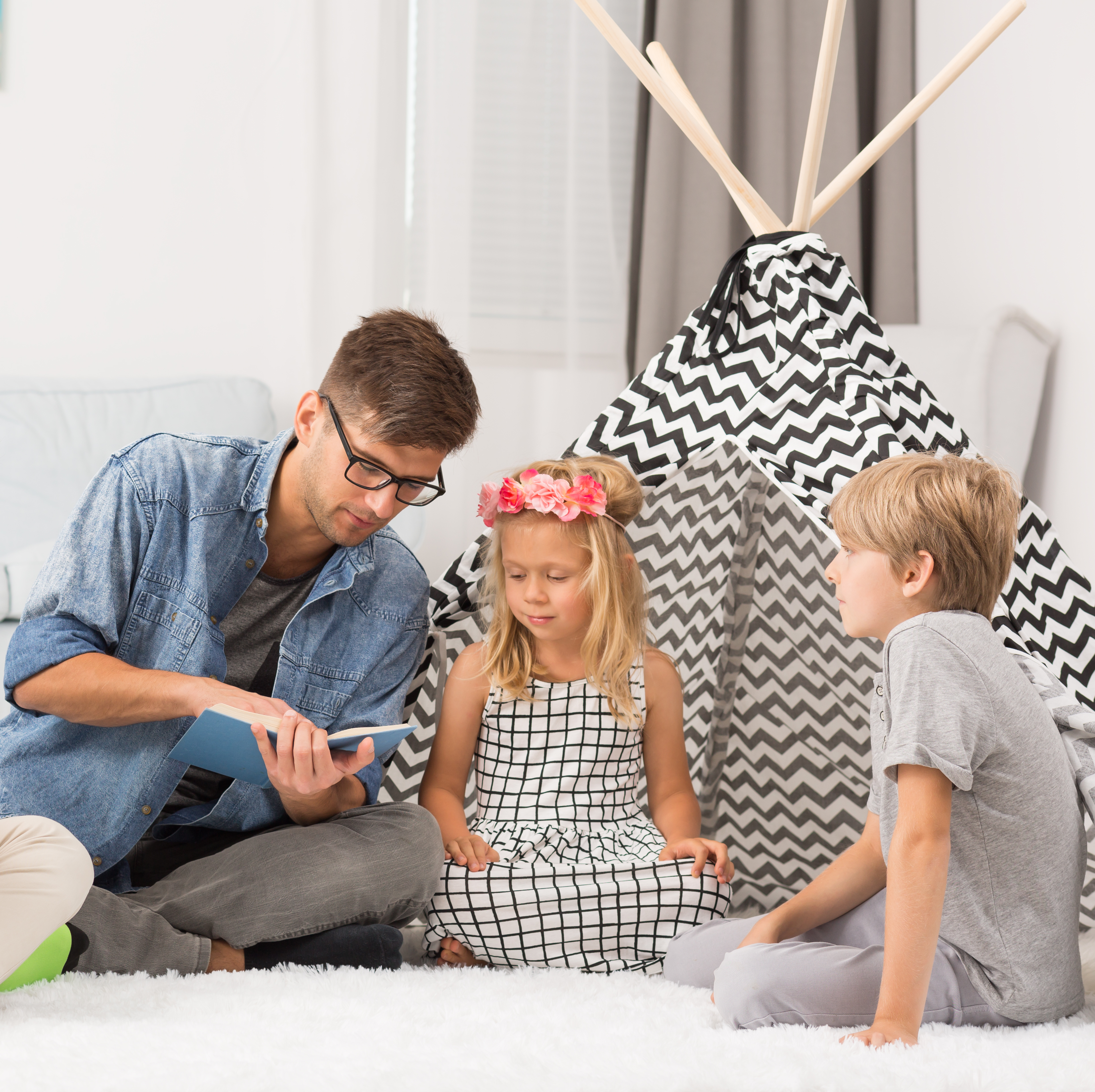 A father reads a book to three of his children.