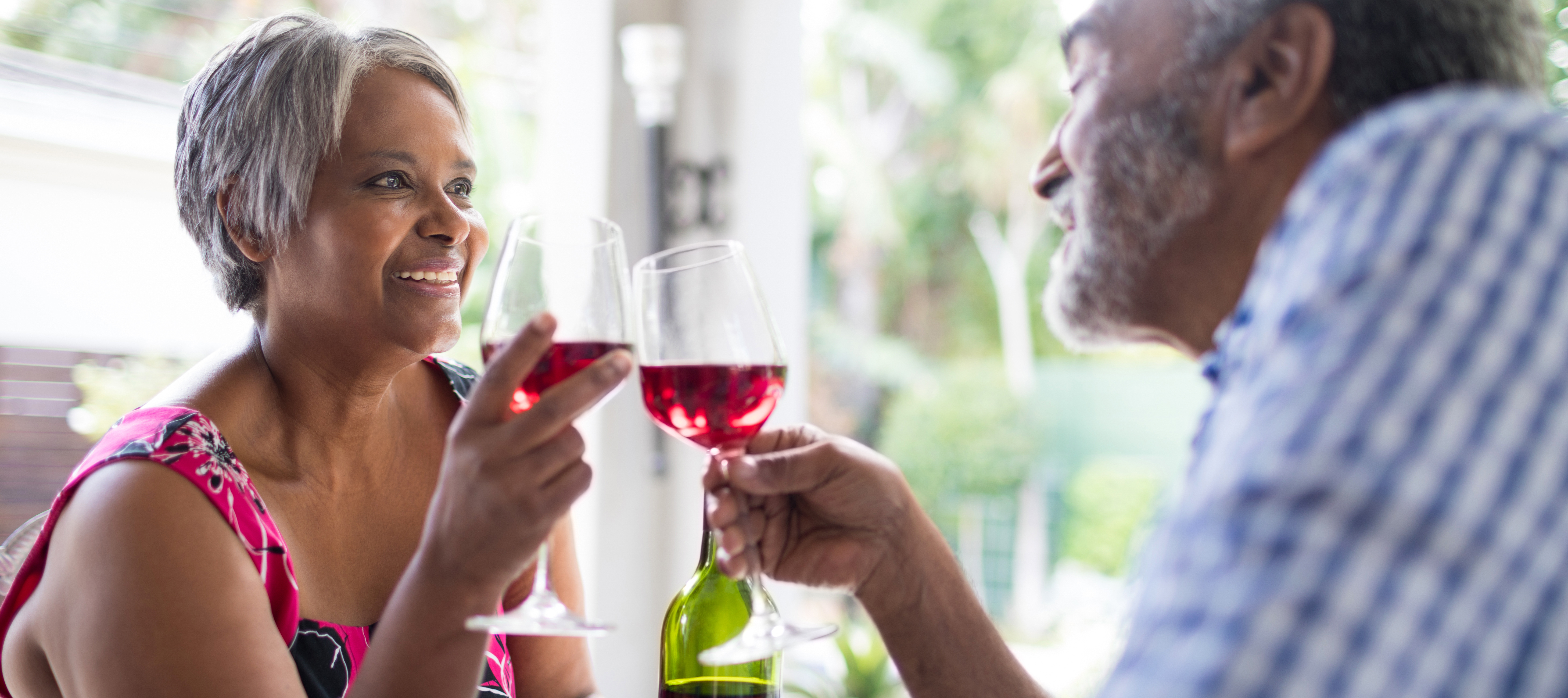 A retired couple enjoys a bottle of wine together.