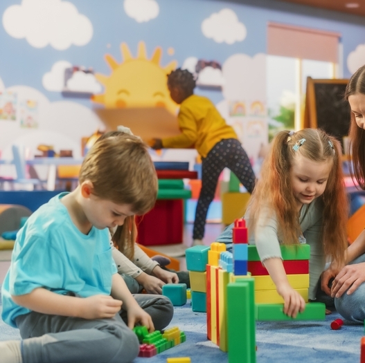 Young children play with colorful blocks in a classroom.