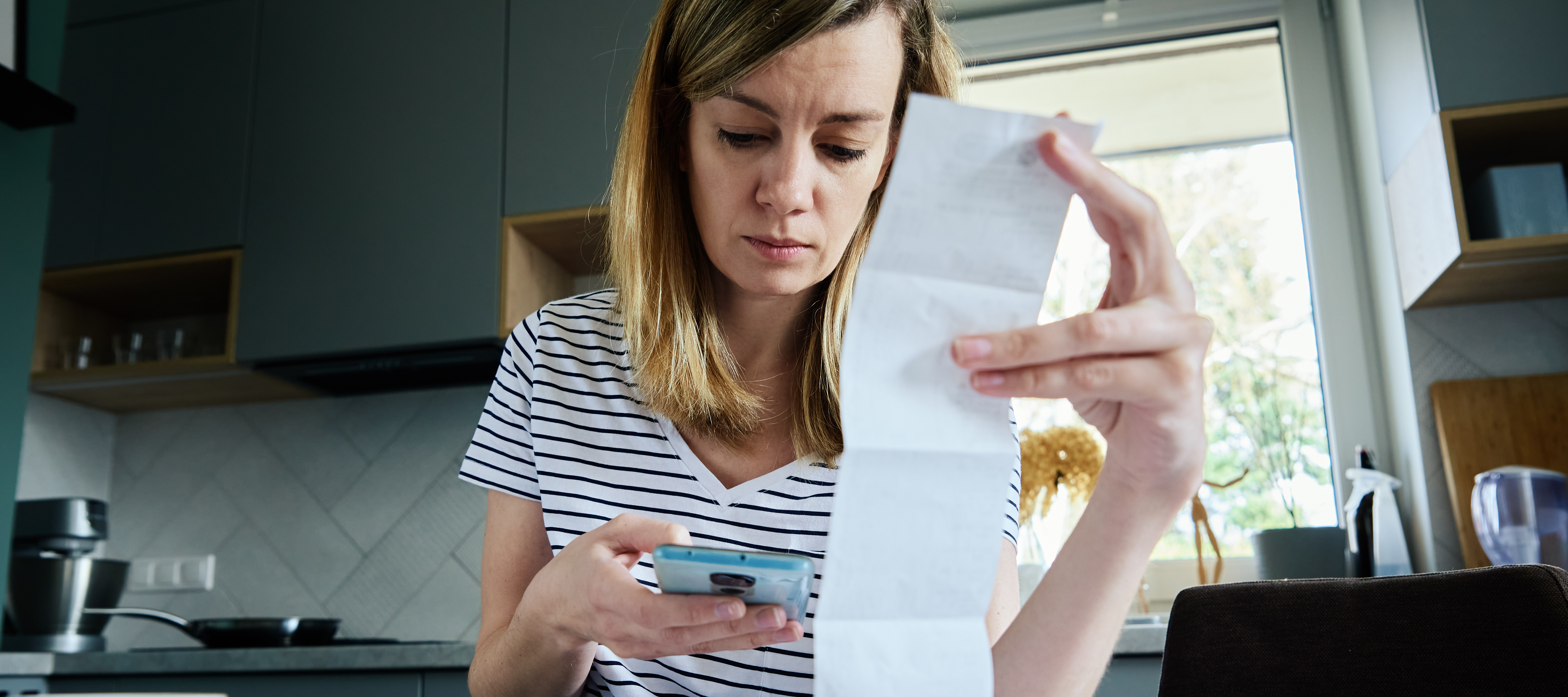 Young woman stressing out looking at her bills and phone.